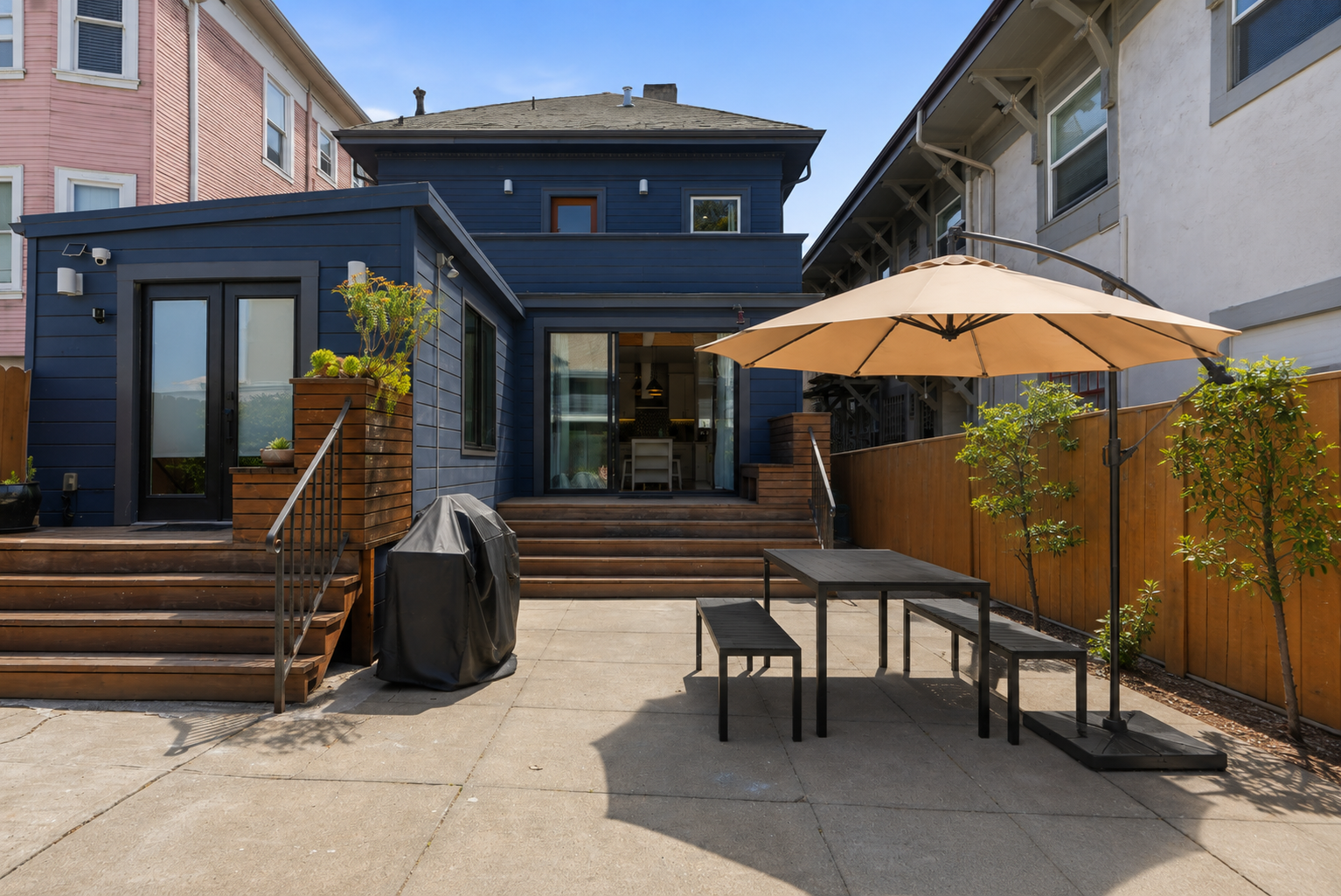 Private backyard patio with shaded dining, deck space, and grill