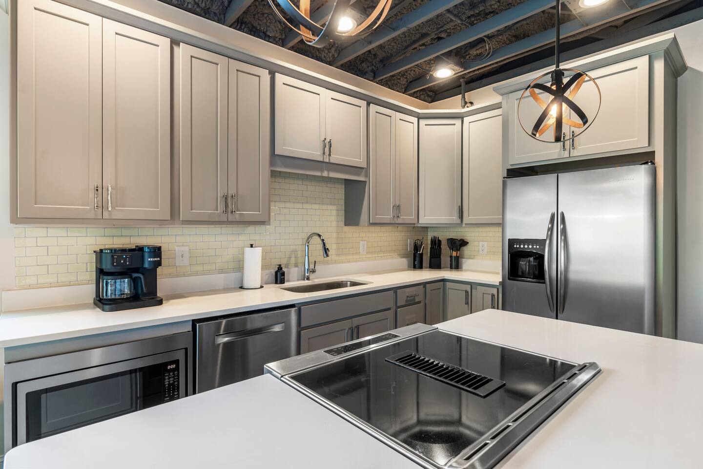 Bright modern kitchen with island, stainless appliances, and designer lighting