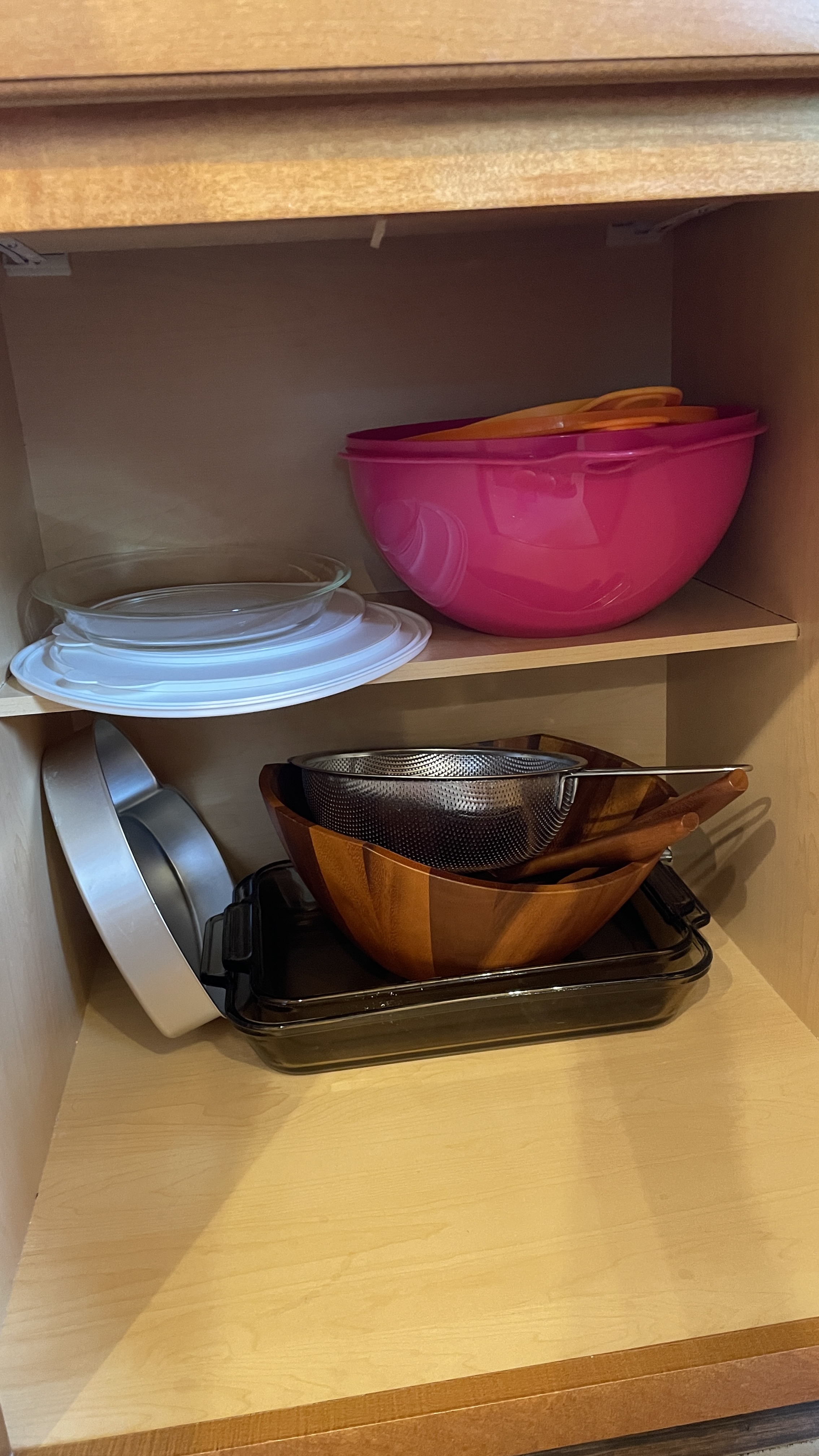 Well-stocked kitchen cabinet with bowls, bakeware, and dining essentials