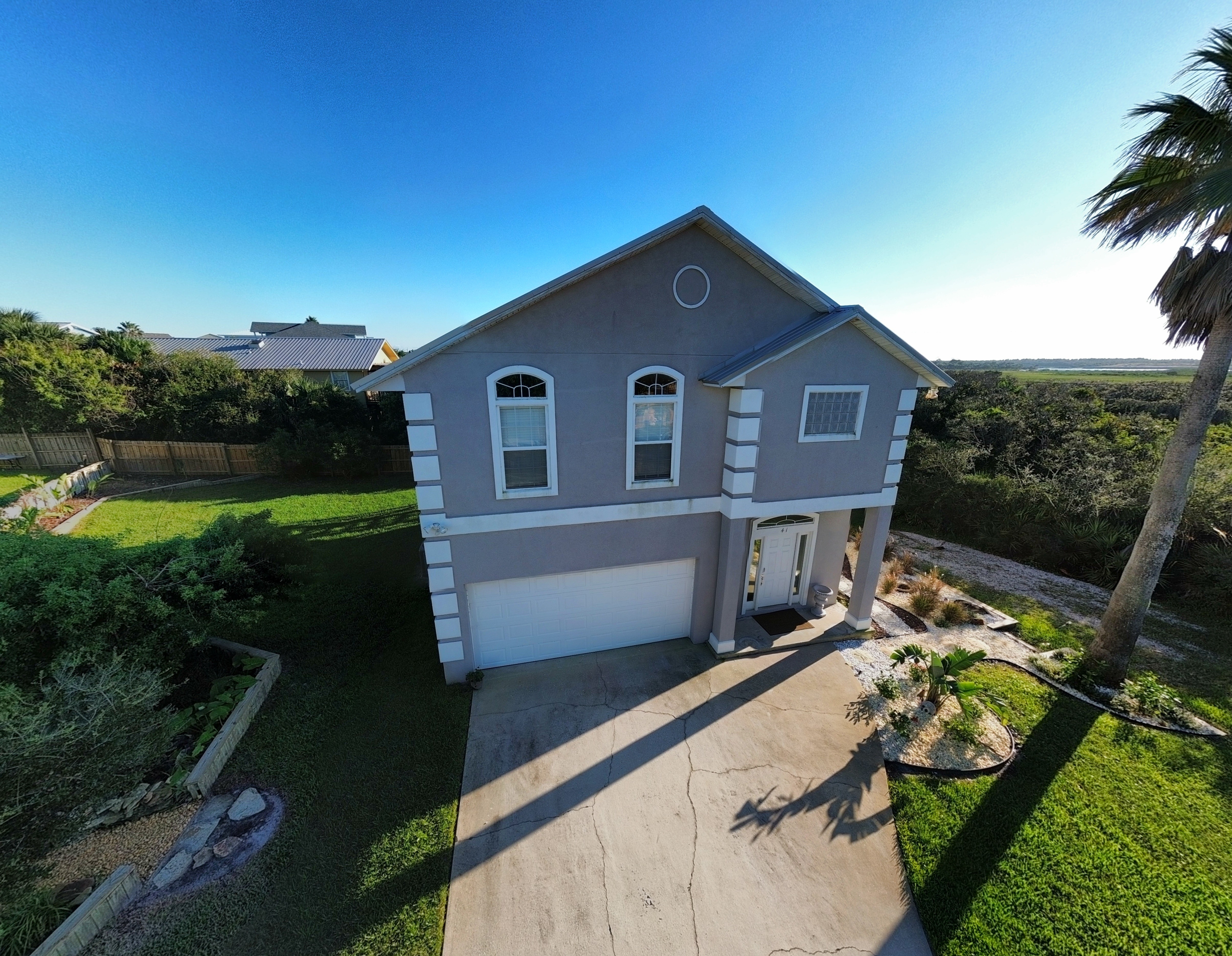 Spacious coastal home with palm trees, parking, and inviting curb appeal