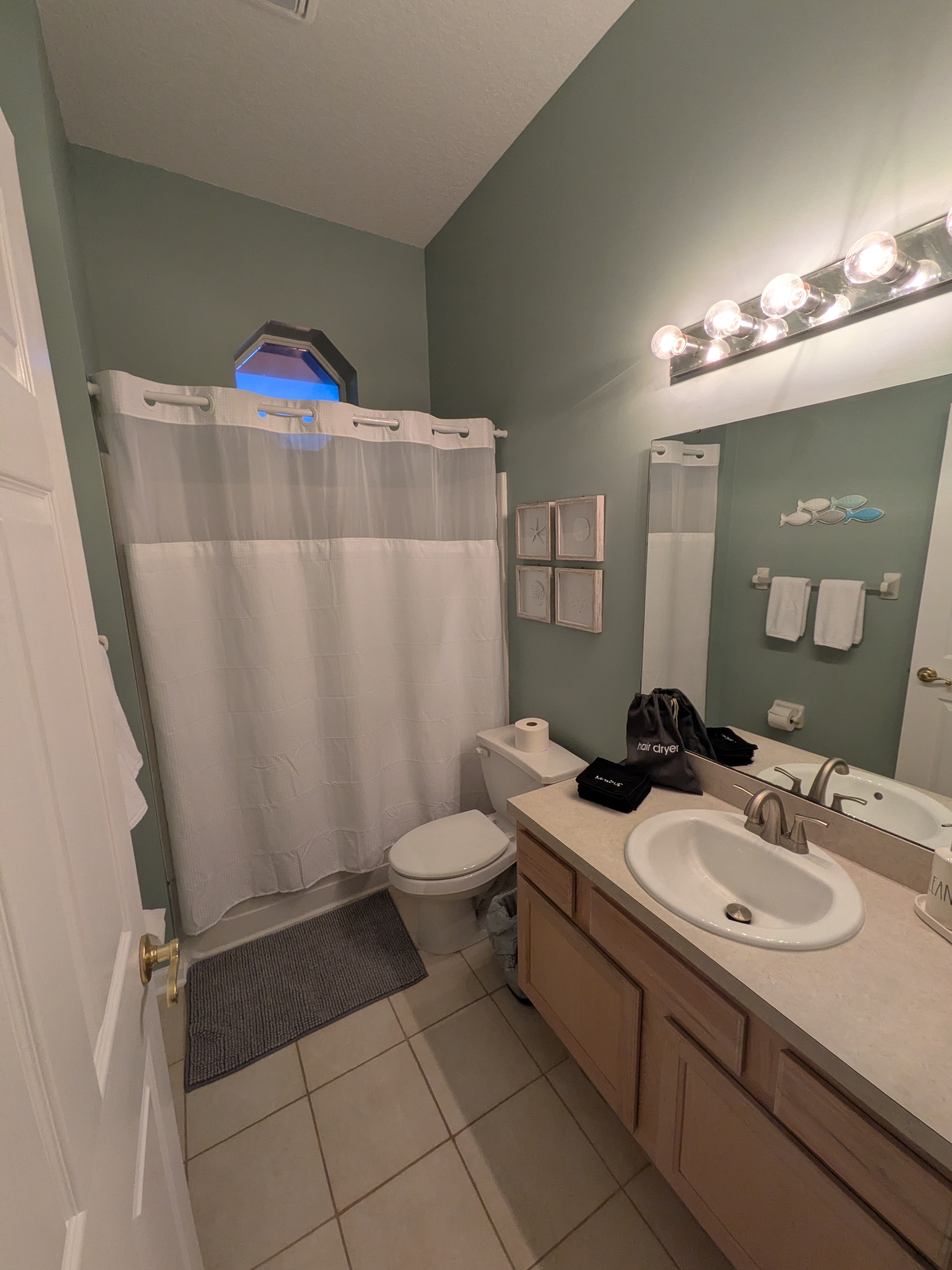 Bright bathroom with spacious vanity, tub-shower combo, and coastal touches