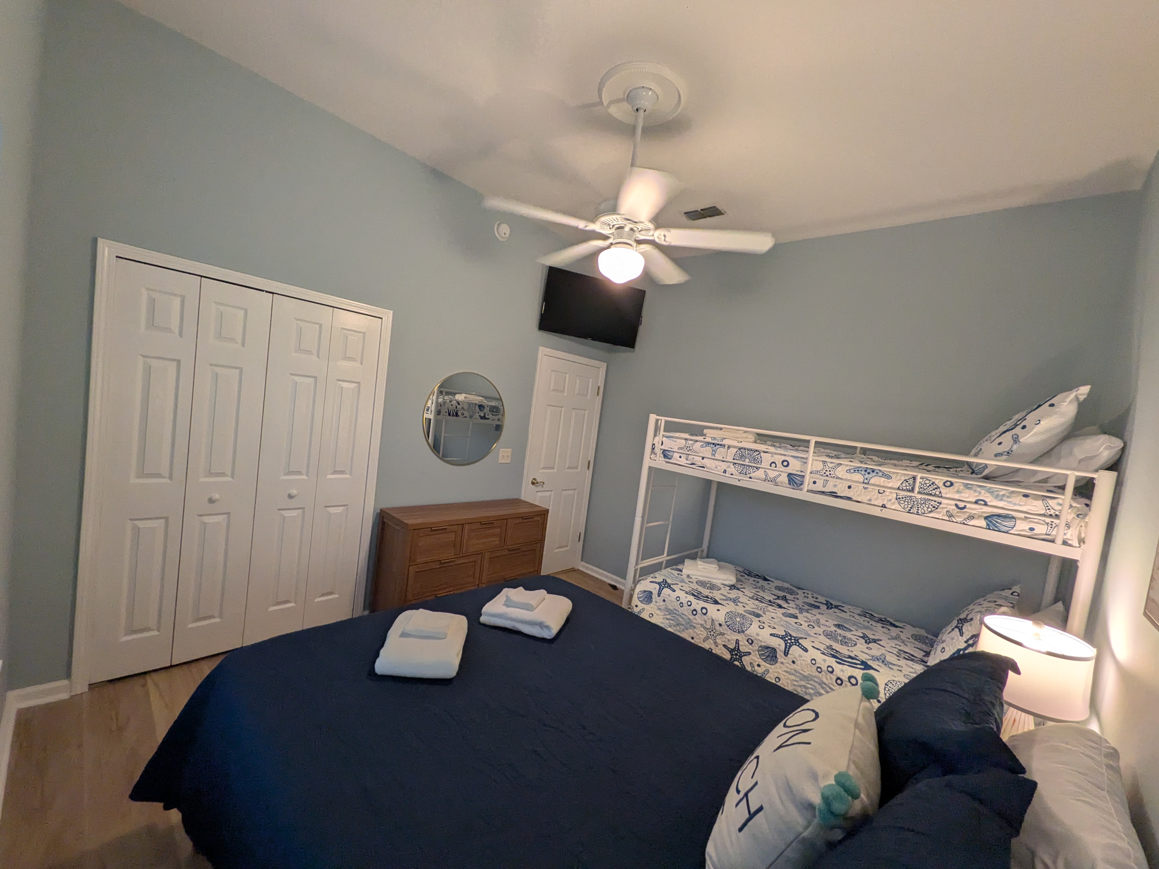 Coastal family bedroom with bunk beds, TV, and ample storage