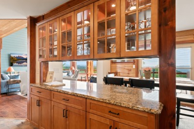 The granite pass-through counter links the kitchen straight to the dining and great room, so plates, drinks and conversation move easily between them all, with custom wood cabinetry underneath keeping the open-concept layout warm rather than sterile.