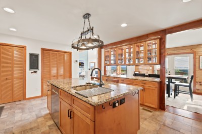 This rustic kitchen flows straight into the dining space, where the table seats six beneath French doors that open onto the deck, keeping the granite island, the cooking, and the conversation all part of one easy, connected space for the whole group.