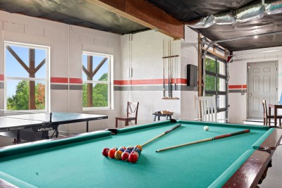 Rack up a game on the slate pool table or trade volleys at ping pong in the game room, where a glass garage door rolls open to leafy outdoor views alongside foosball, darts, a card table, board games, and a fireplace for cooler nights and rainy days.