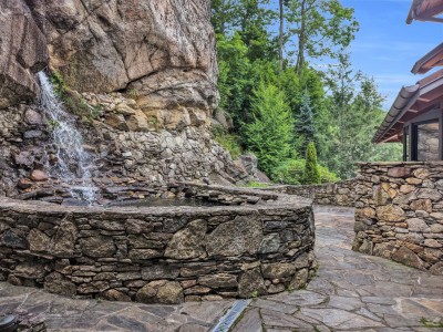 A private sixty-foot waterfall spills down the granite cliff right beside the house, filling the stone pool below with the sound of falling water.