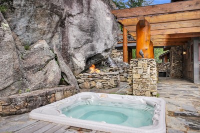 Soak in the hot tub as firelight flickers against the granite cliff and the timber pavilion glows just beyond.