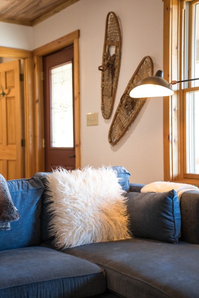 Rustic-chic living room with a plush sectional and leather armchairs, wood ceilings and stone details add the lodge charm that makes this the spot everyone gathers.