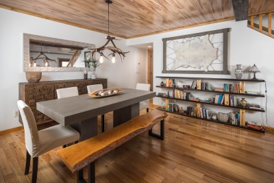 Rustic-modern dining room centered on a live-edge wood bench and warm timber details, the kind of table that pulls everyone in for long dinners, board games, and easy mountain-lodge charm after a day on the trails.
