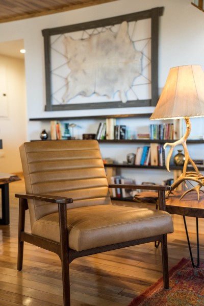 Warm reading nook with a leather armchair tucked beside built-in bookshelves, rustic wood details all around, the perfect quiet corner for a slow afternoon with a book.