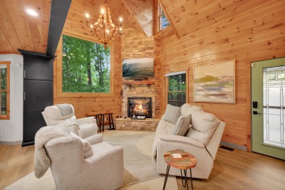 Vaulted pine, a stone chimney that climbs to the ridge, and a fire you can see from the kitchen. The cabin's warmest corner in every season.