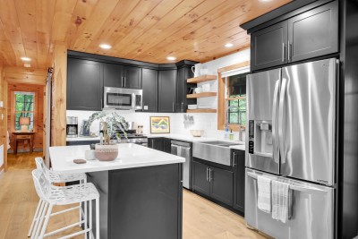 Everything you need to cook a real meal, laid out around a big island. Open shelving keeps the plates and mugs within reach.