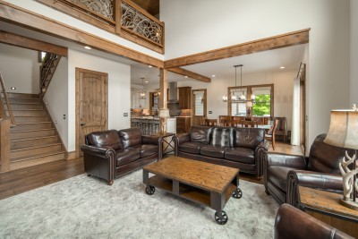 Deep leather sofas and club chairs circle a reclaimed-wood coffee table, with the loft's mountain-laurel railing floating overhead.
