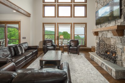 Nine panes of stacked glass frame the ridge from the sofa, with the covered deck a step outside.