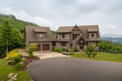 Red-trimmed windows and cedar shake gables, with the ridgeline dropping to blue layers at the right.