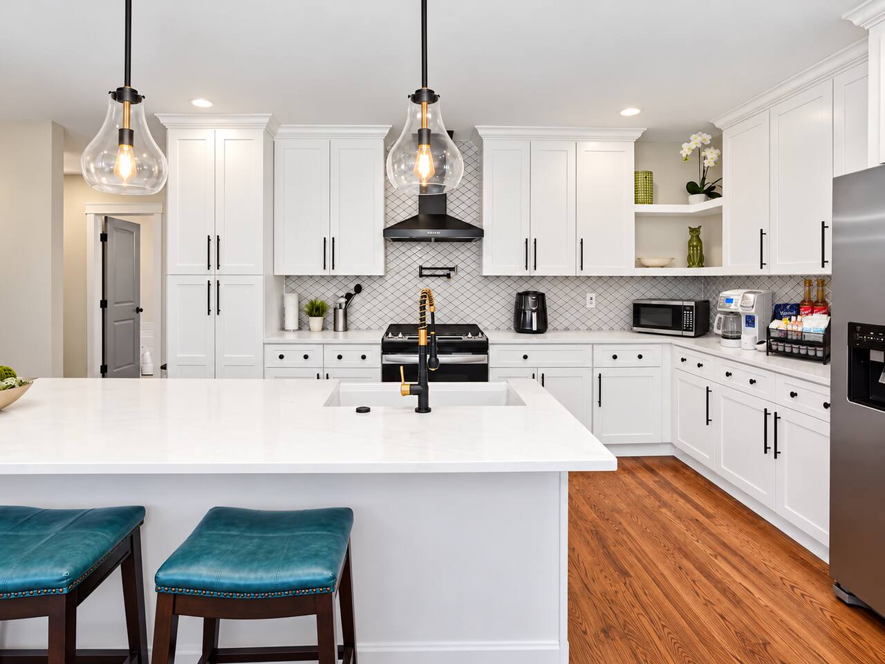 Prepare meals in this beautiful kitchen featuring white cabinetry, quartz countertops, stainless steel appliances, and a spacious island.