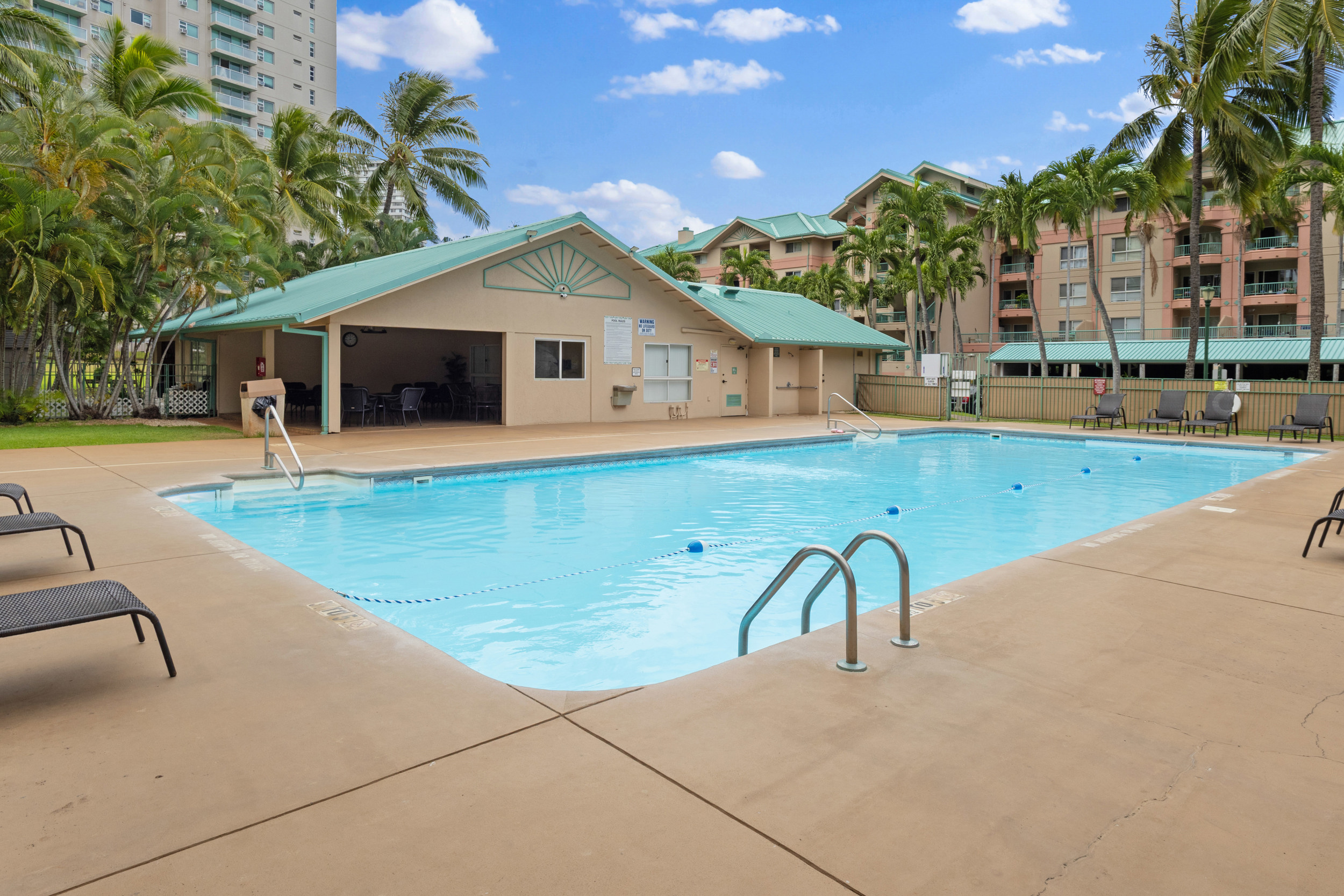 Resort-style pool with palm trees, lounge deck, and shaded pavilion