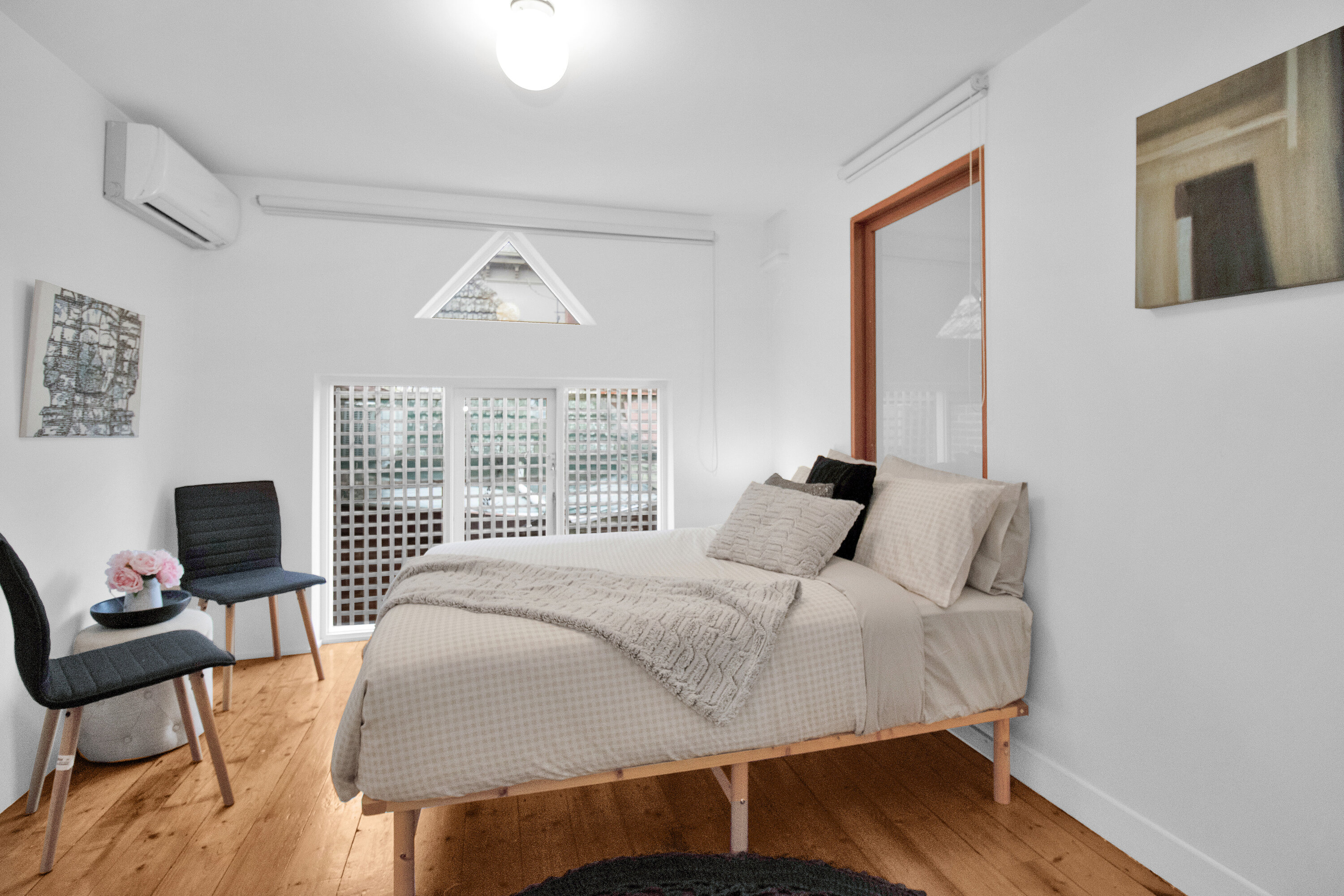 Bright minimalist bedroom with AC, wood floors, and cozy modern styling