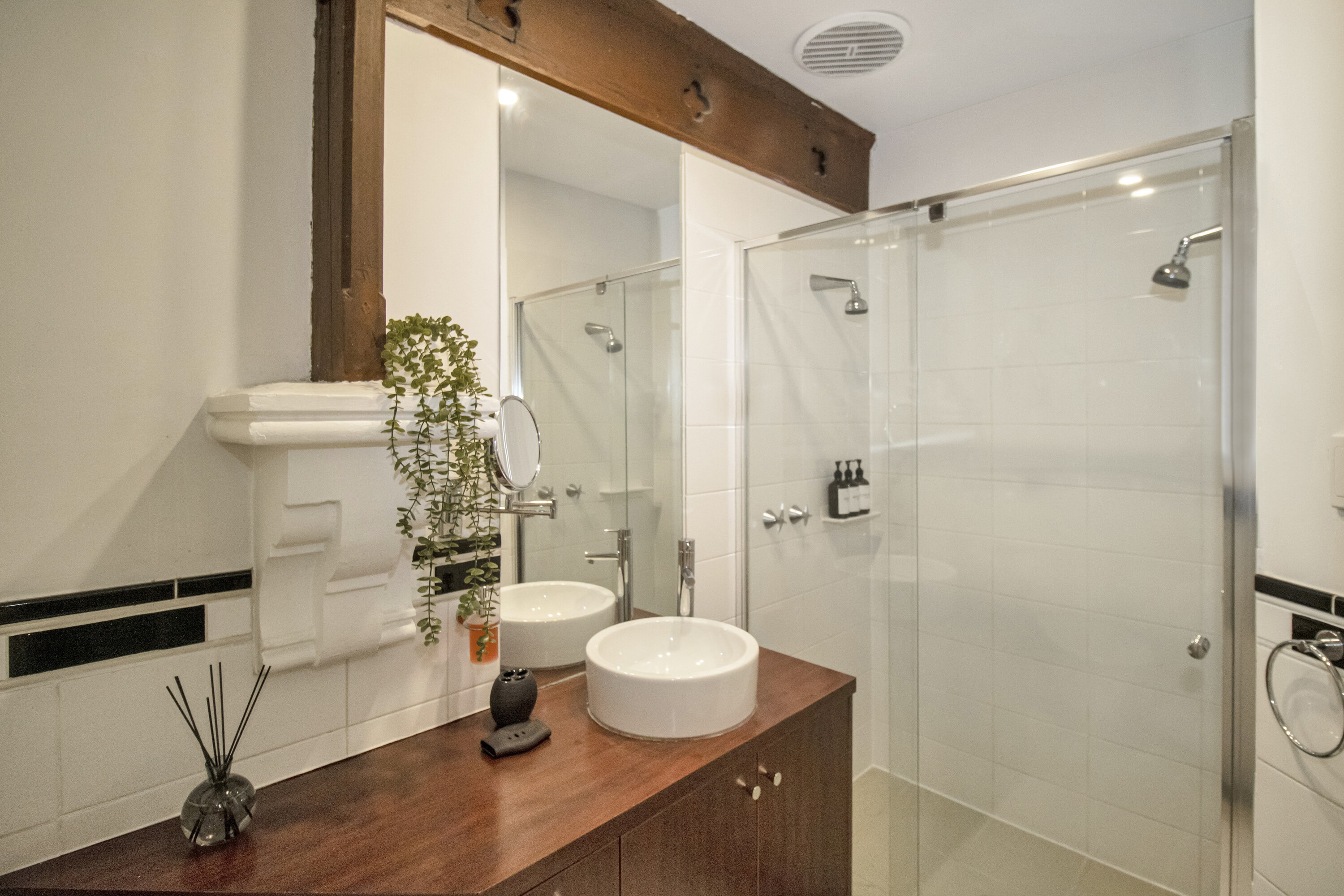 Bright modern bathroom with glass shower and rustic wood accents