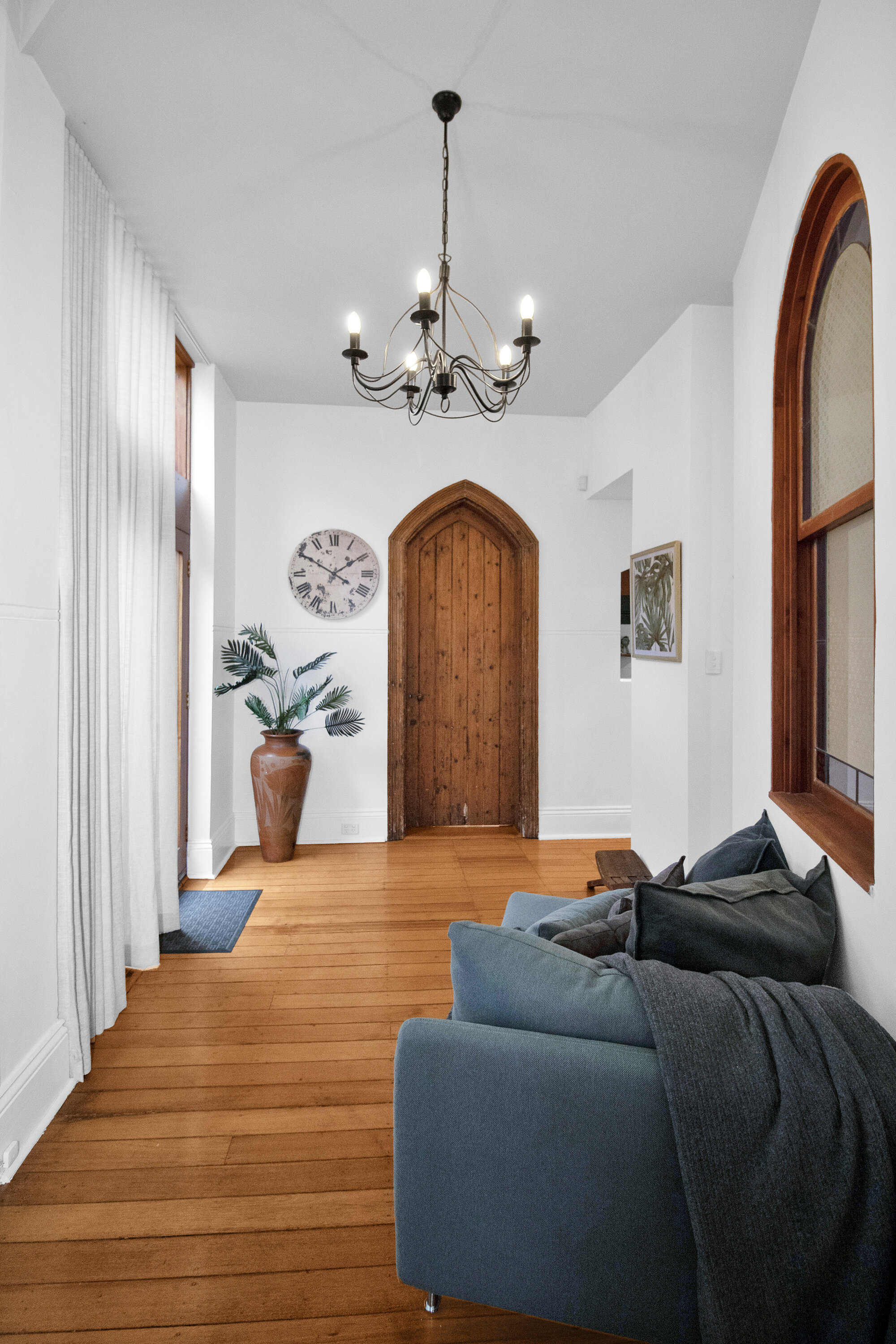 Bright entry hall with soaring ceilings, timber floors, and arched charm