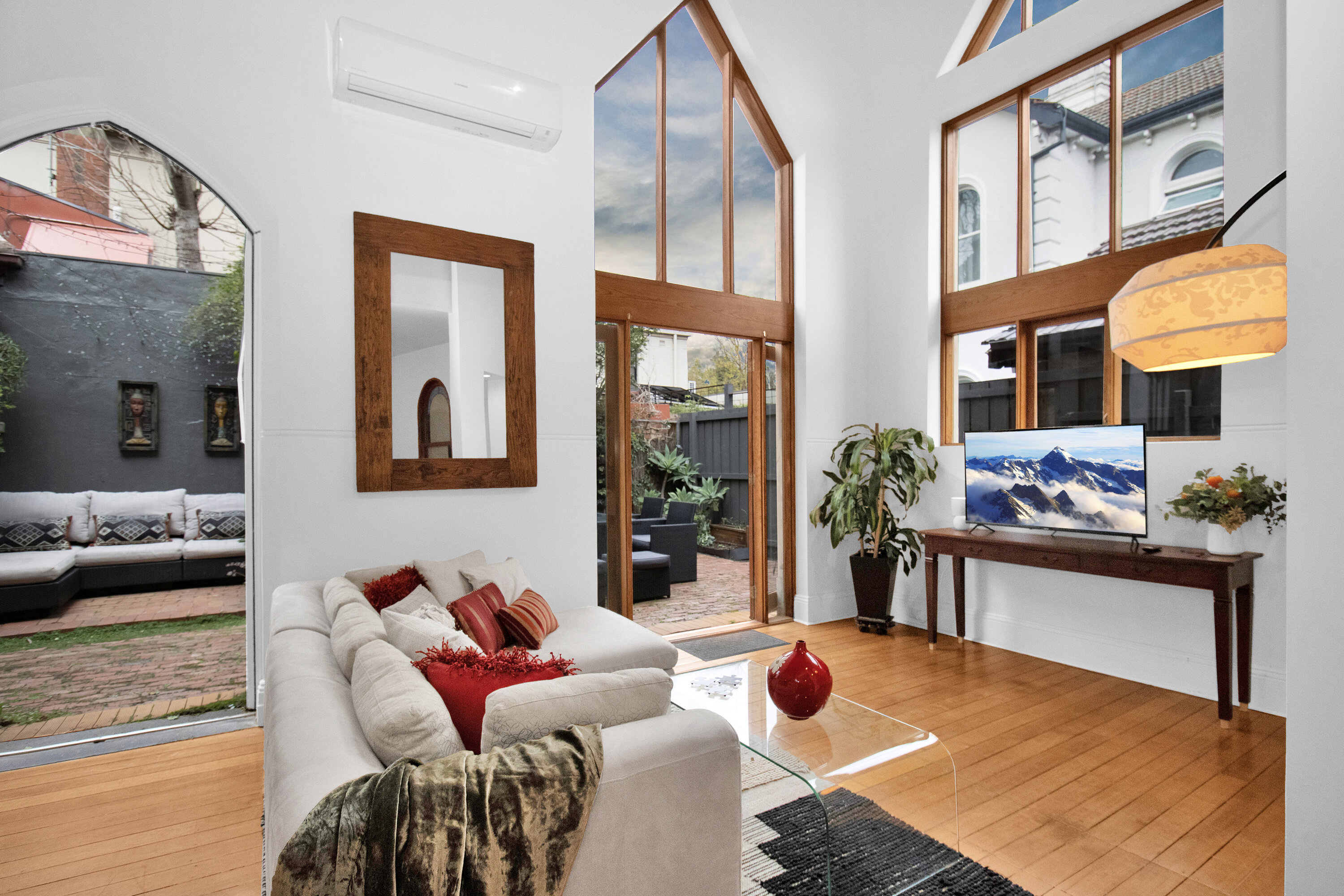 Sunlit loft-style living room with soaring windows and courtyard access