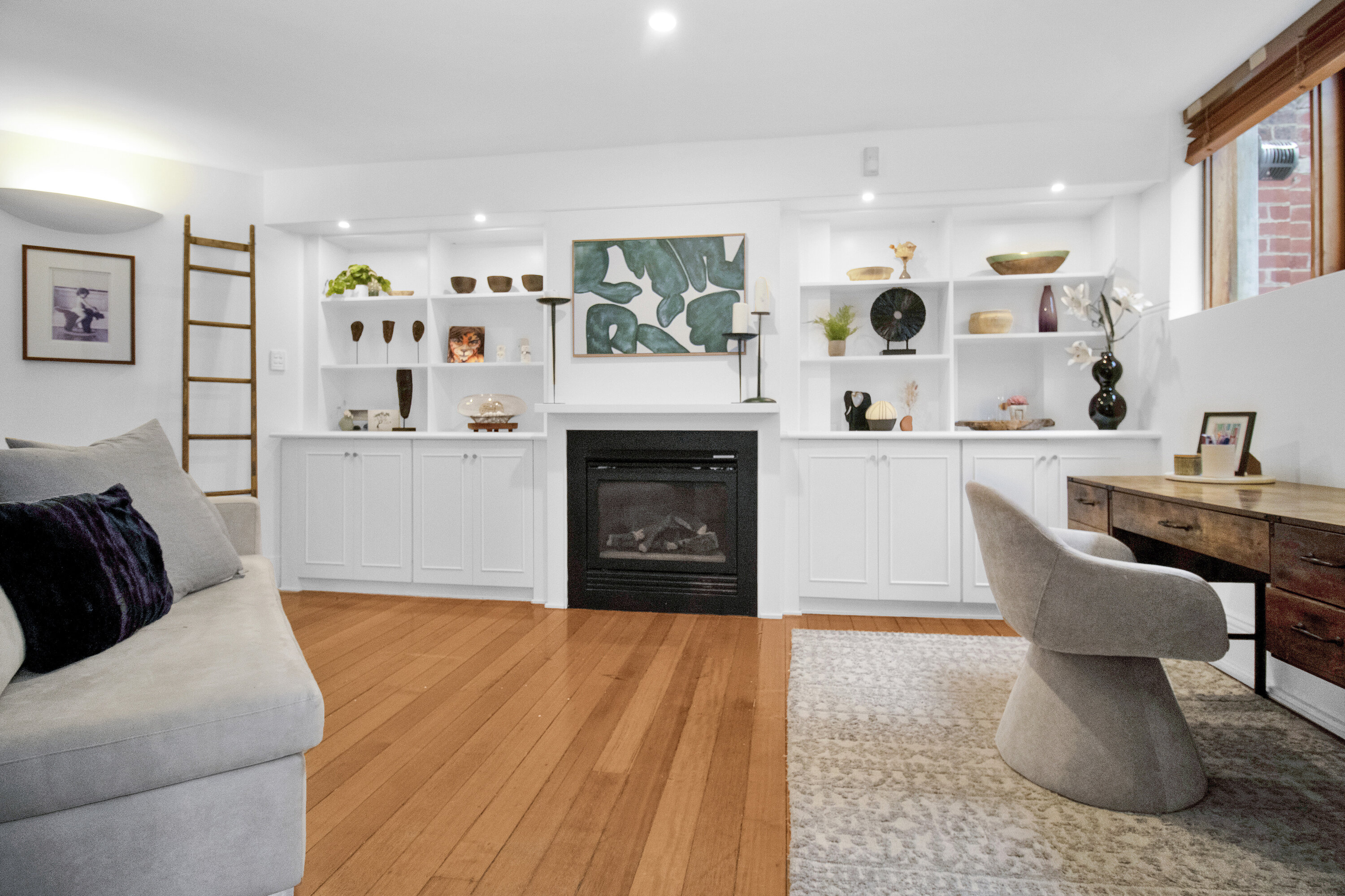 Bright living room with fireplace, built-ins, and stylish work desk