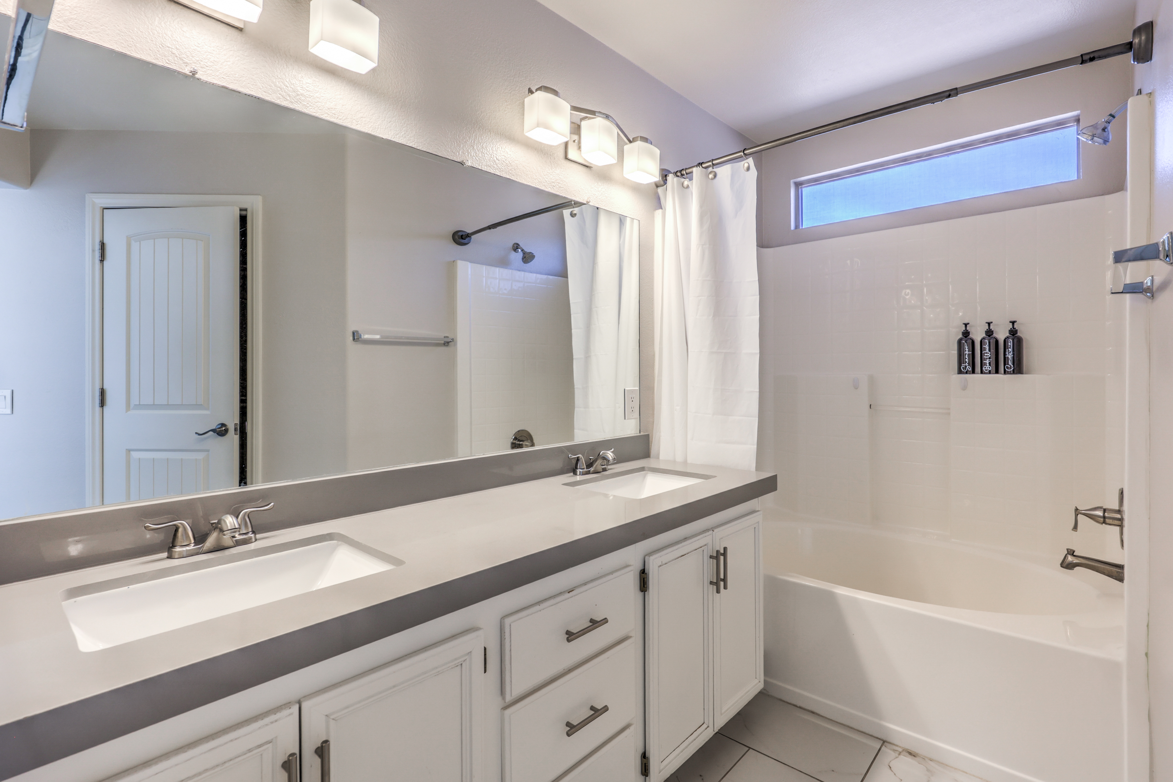 Bright modern bathroom with double vanity and tub-shower combo