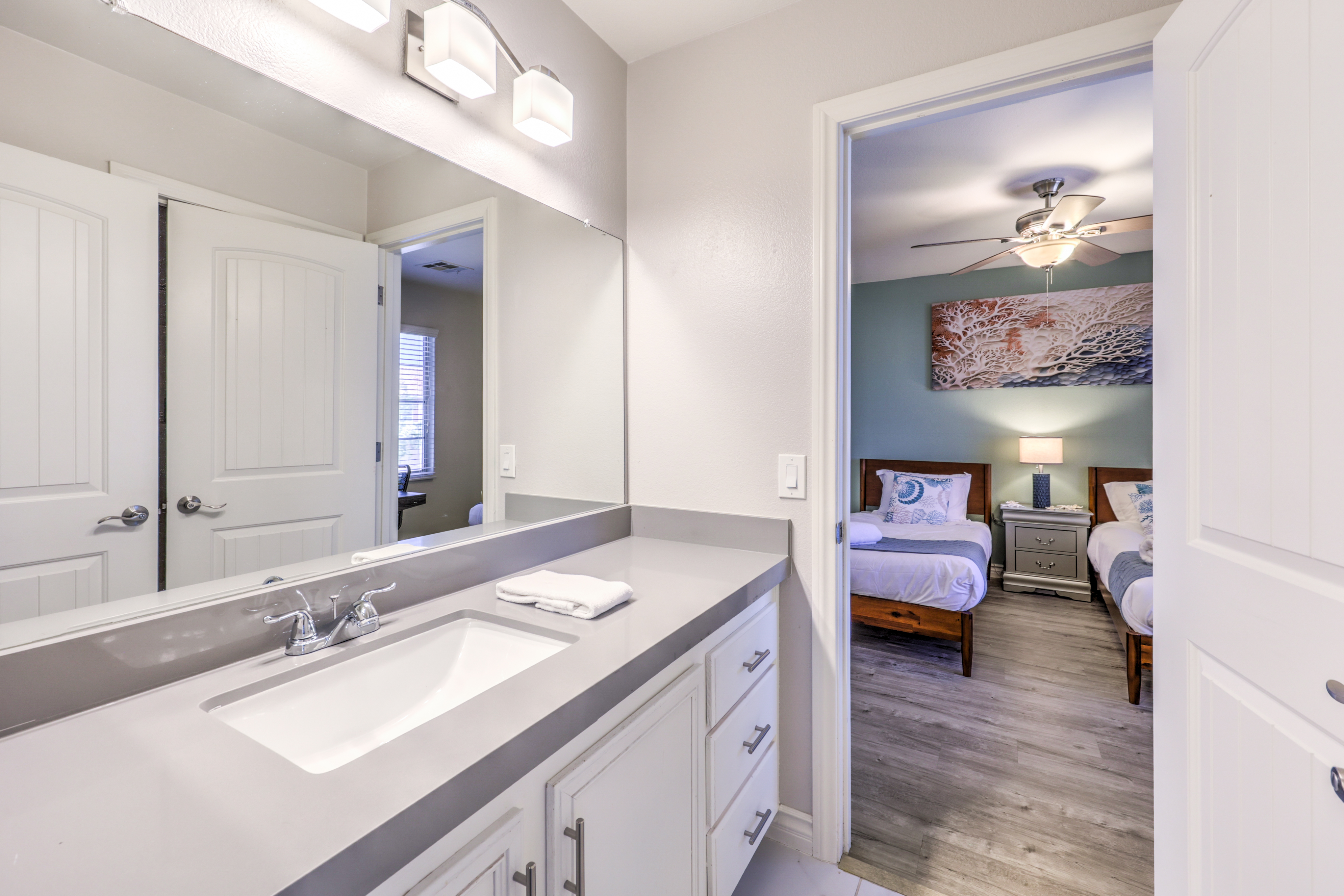 Bright bath with spacious vanity connected to a cozy twin bedroom