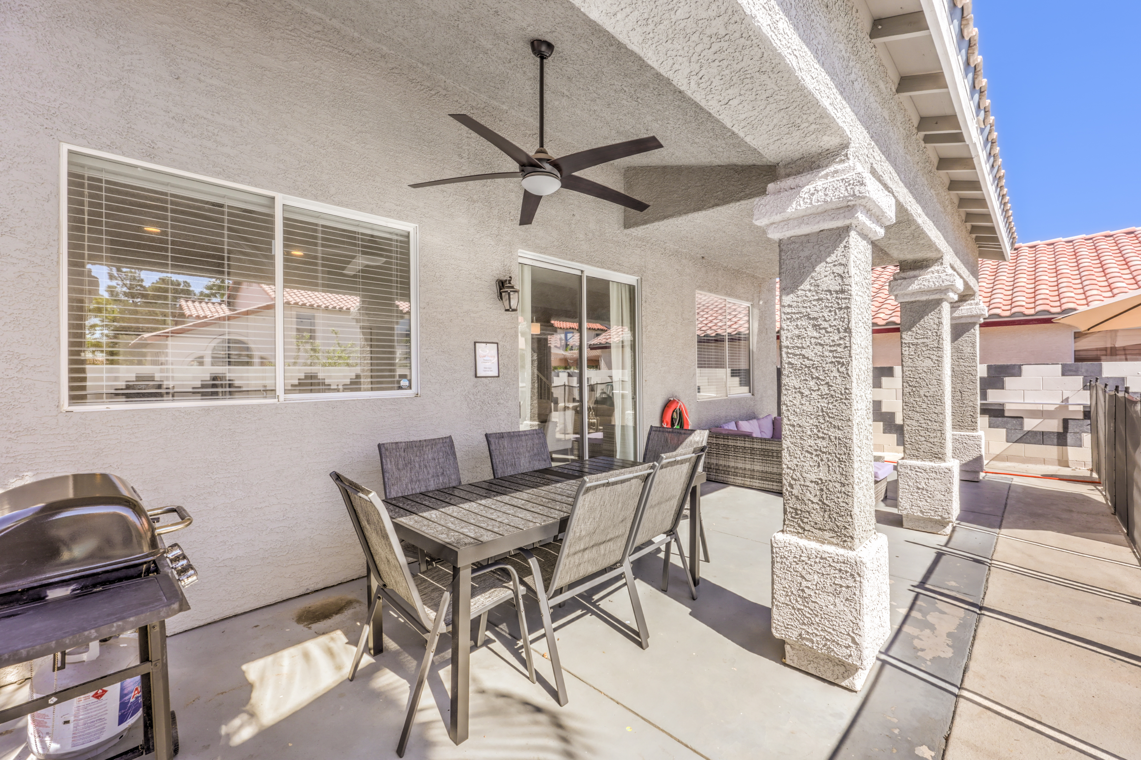 Covered patio with dining table, grill, ceiling fan, and cozy lounge seating