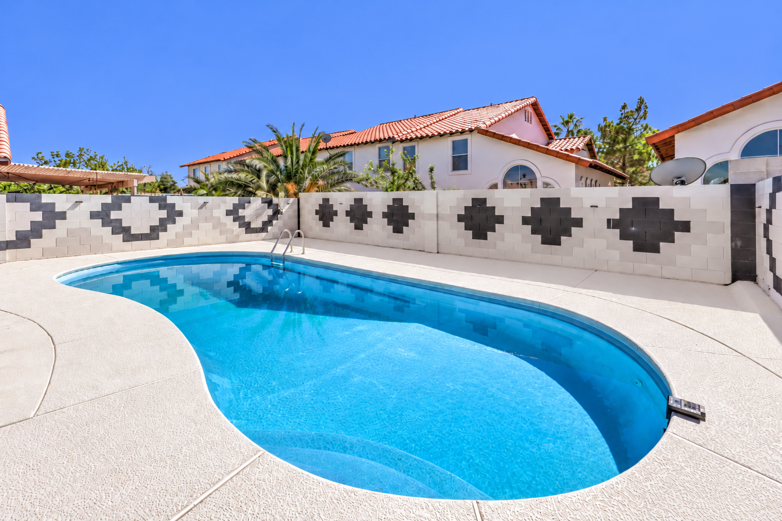 Private sunny backyard pool with stylish privacy wall