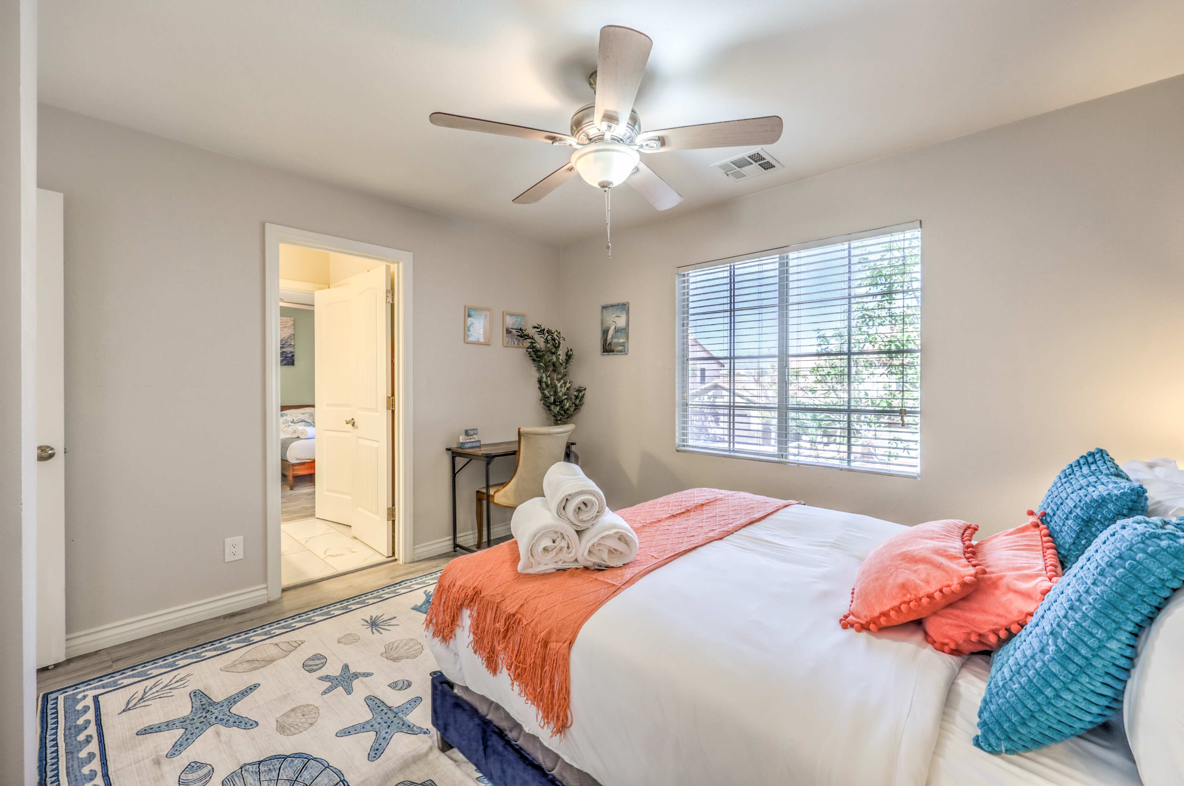 Bright coastal bedroom with natural light, ceiling fan, and beachy decor