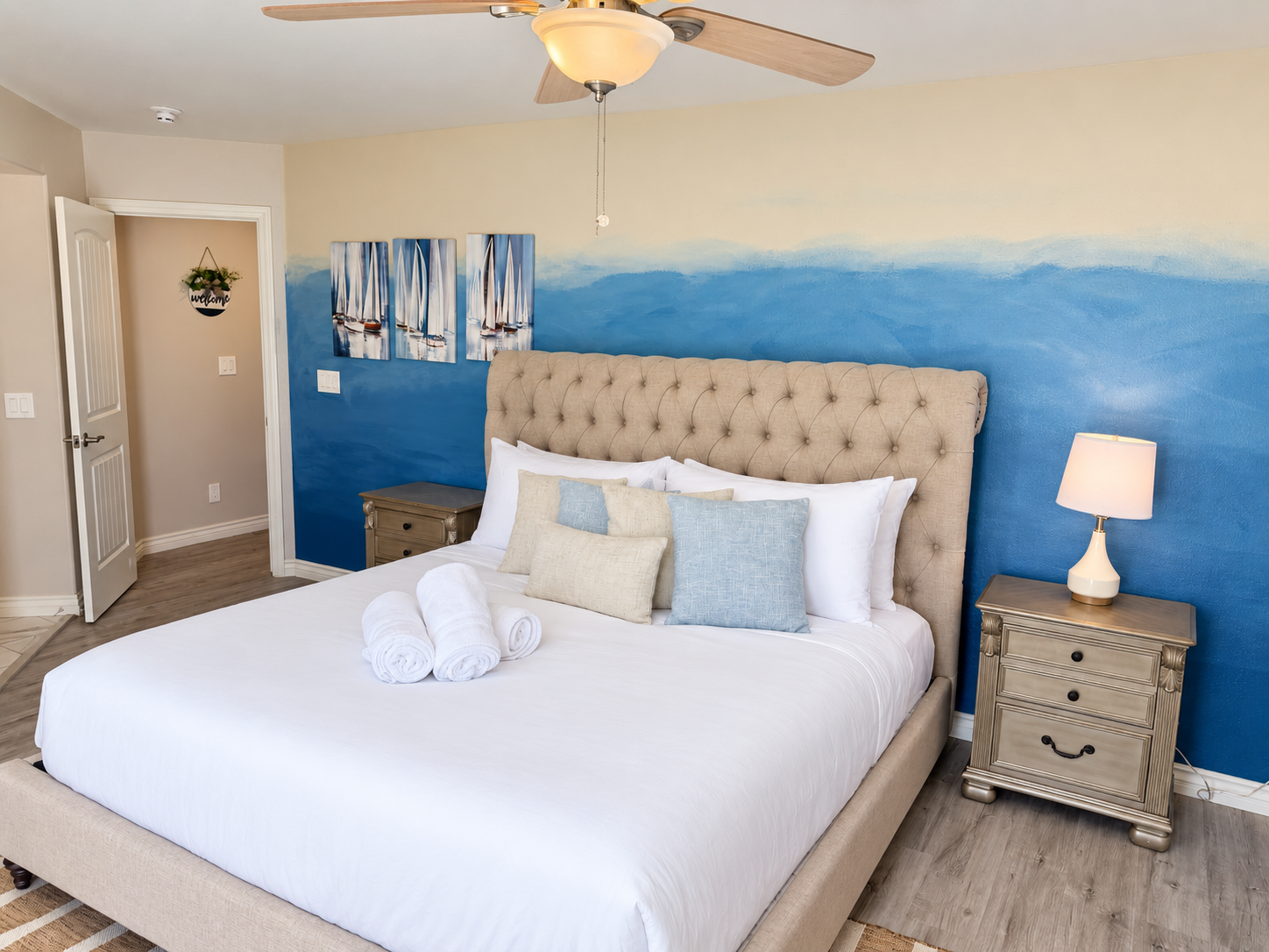 Coastal king bedroom with plush linens, blue accent wall, and serene style
