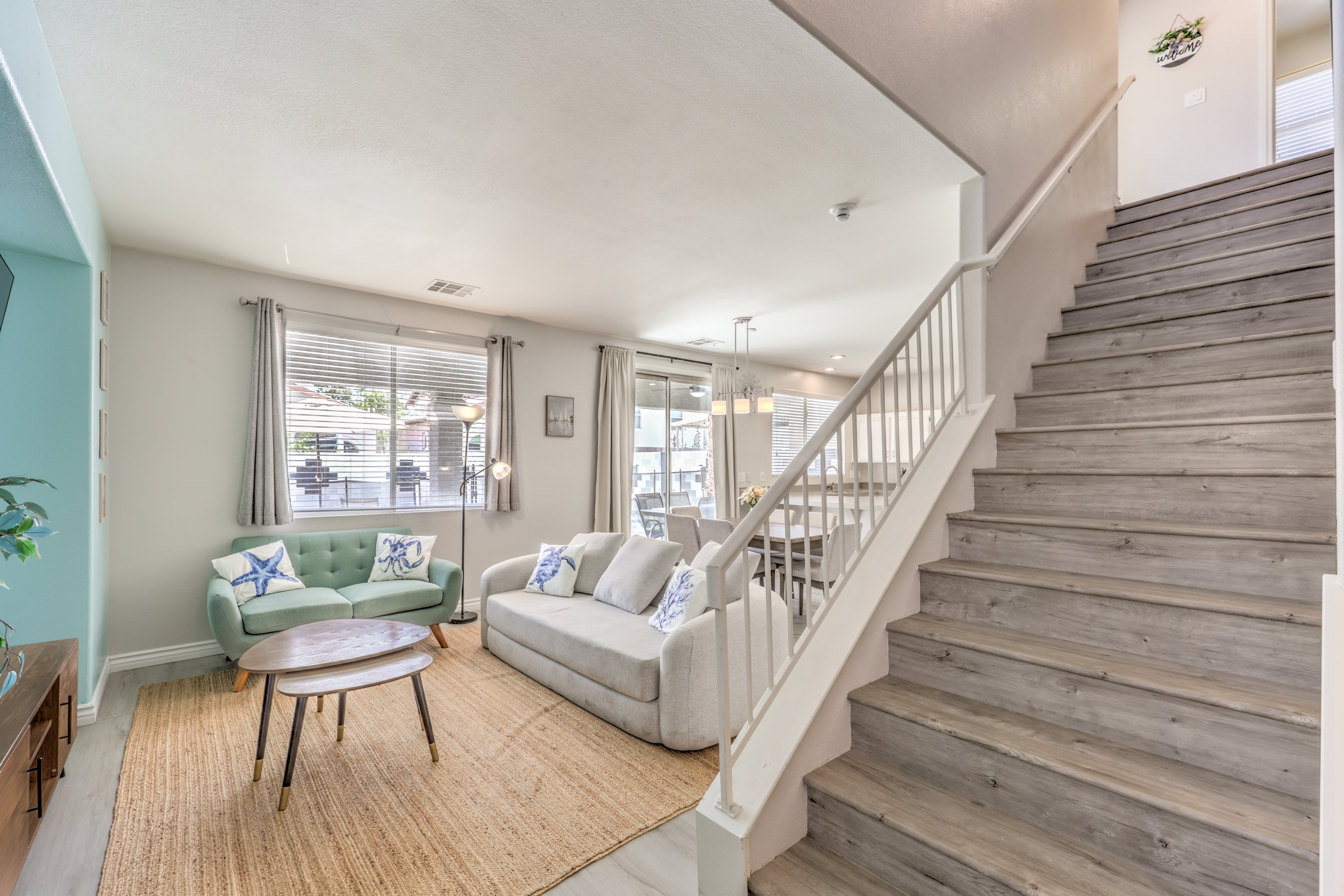 Bright open living area with cozy seating, dining space, and modern staircase