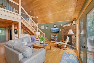The great room is the hub of the main level: the staircase climbs to the loft, the kitchen and dining area sit just around the corner, and there is enough seating on the big sectional that nobody has to fight for the best spot by the fire.