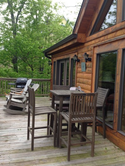 Private wooded deck with outdoor dining, Adirondack chairs, and grill