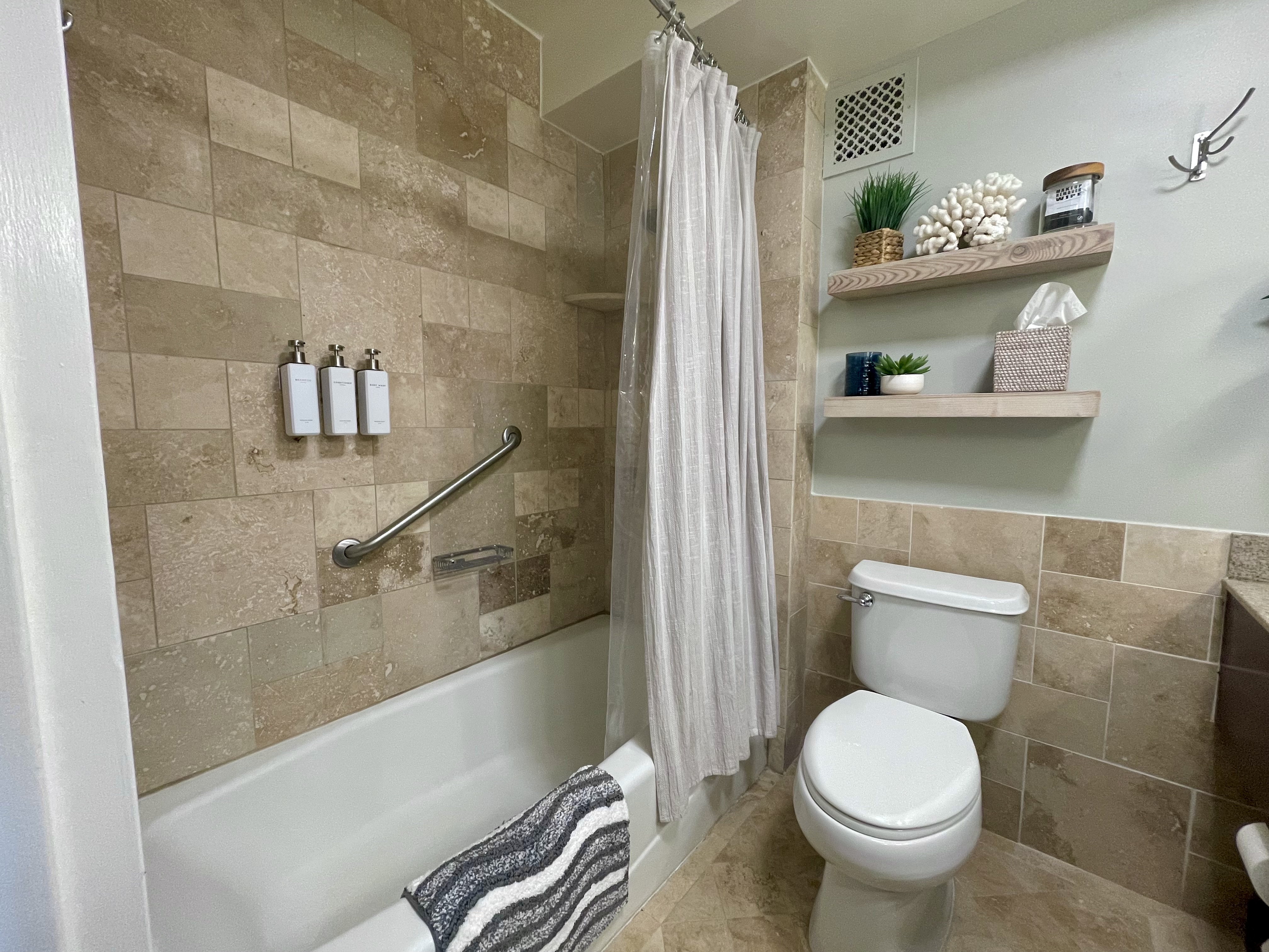 Spa-inspired bathroom with tiled tub, shelving, and guest-friendly touches