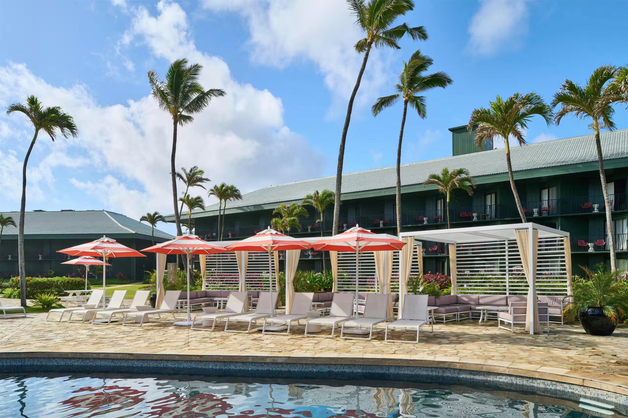 Resort-style pool with cabanas, loungers, and swaying palm trees