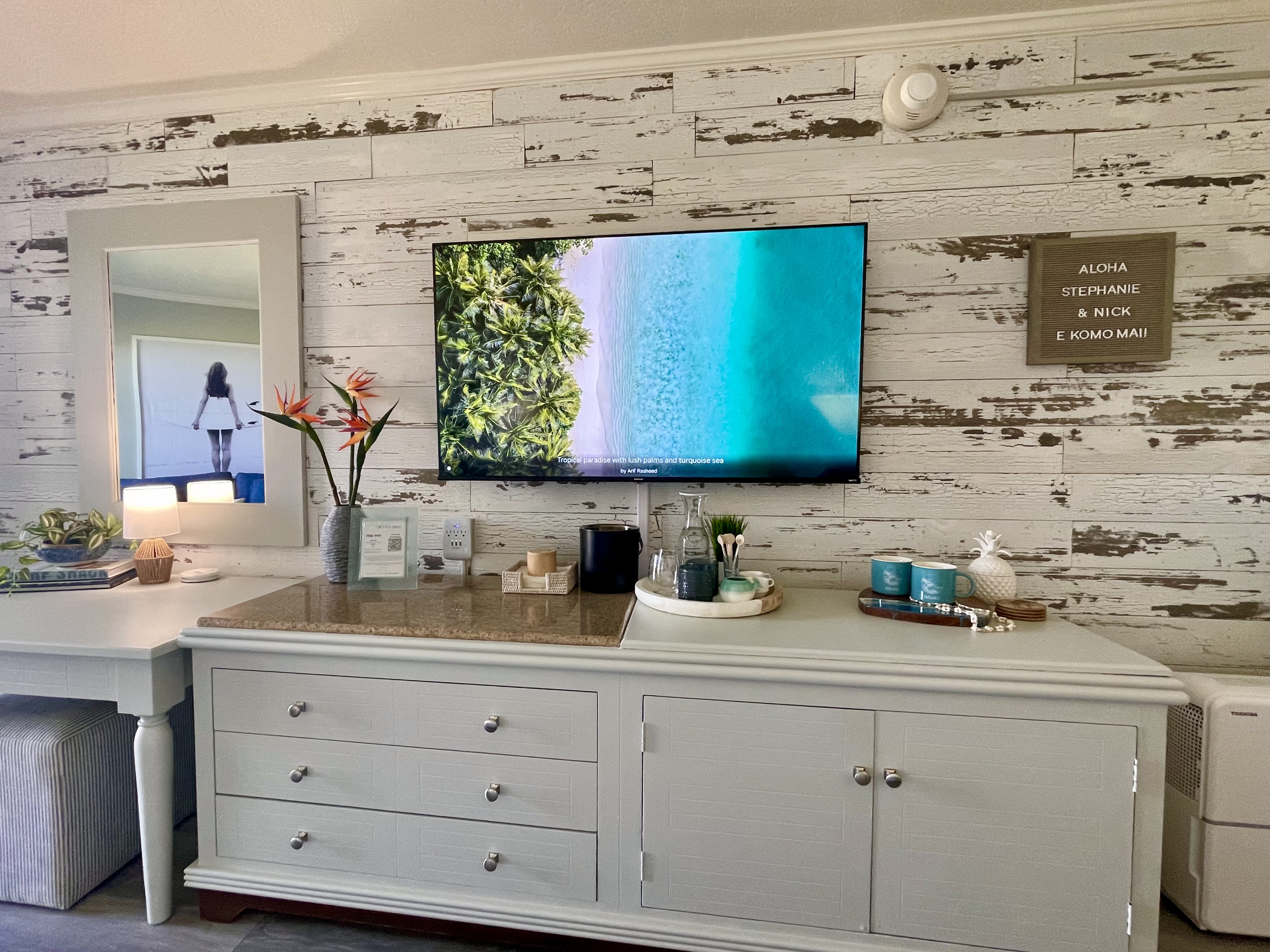 Coastal-chic room with big TV, vanity space, and inviting island decor