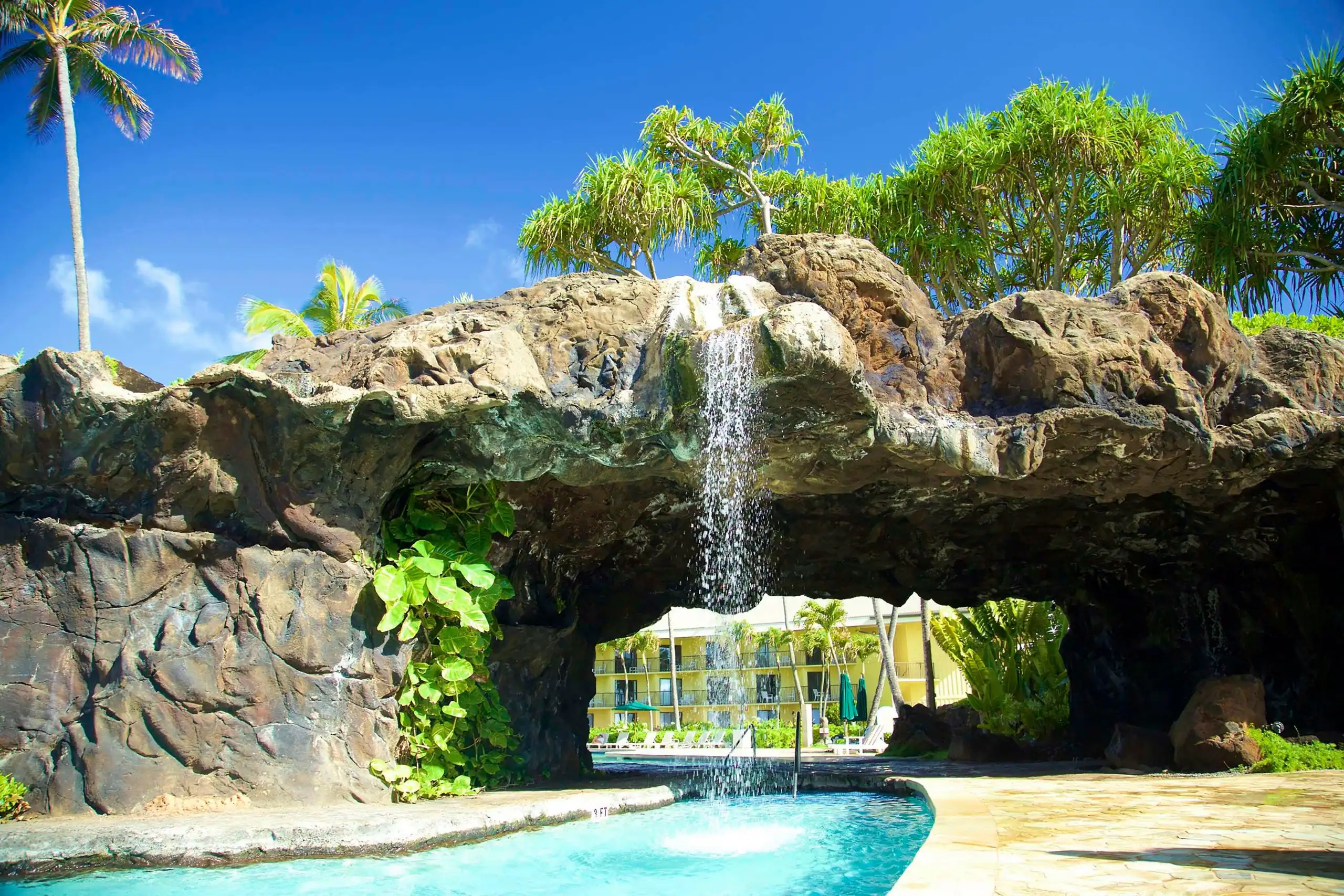 Resort-style pool with tropical grotto waterfall and island vibes