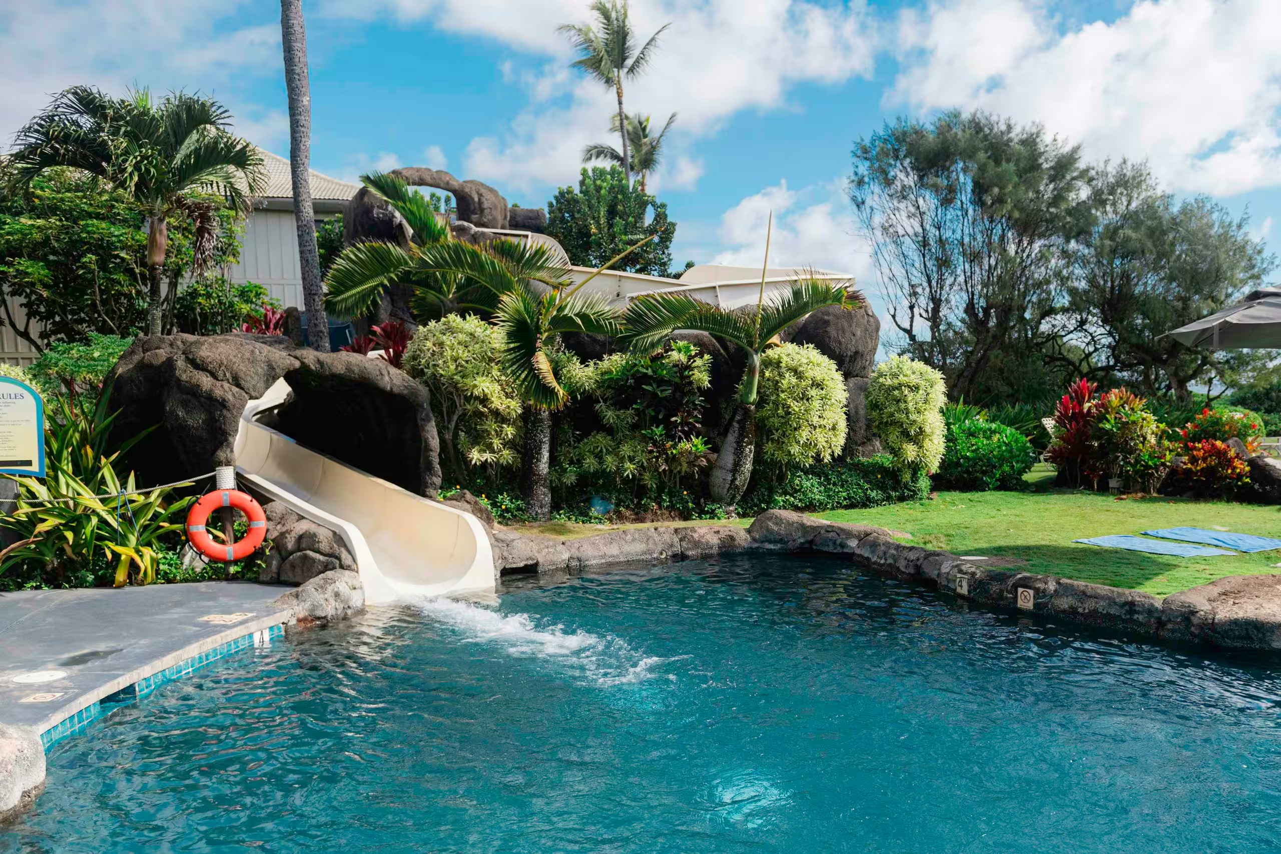 Tropical pool with waterslide, lush gardens, and resort-style ambiance