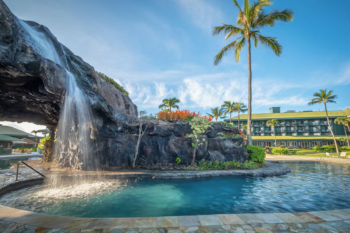Tropical resort pool with rock waterfall and lush island-style setting