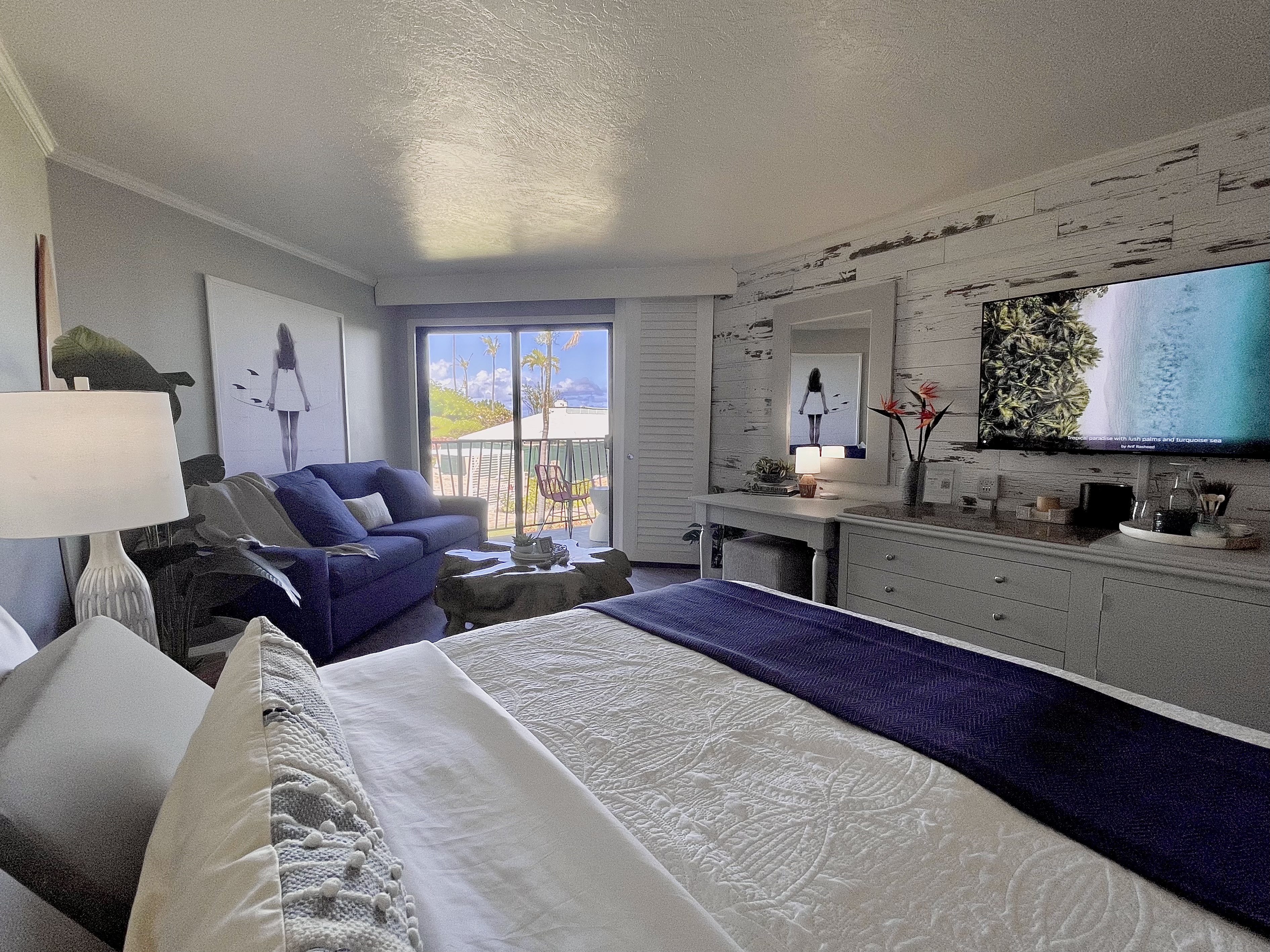 Bright coastal bedroom with balcony, ocean view, and cozy lounge area