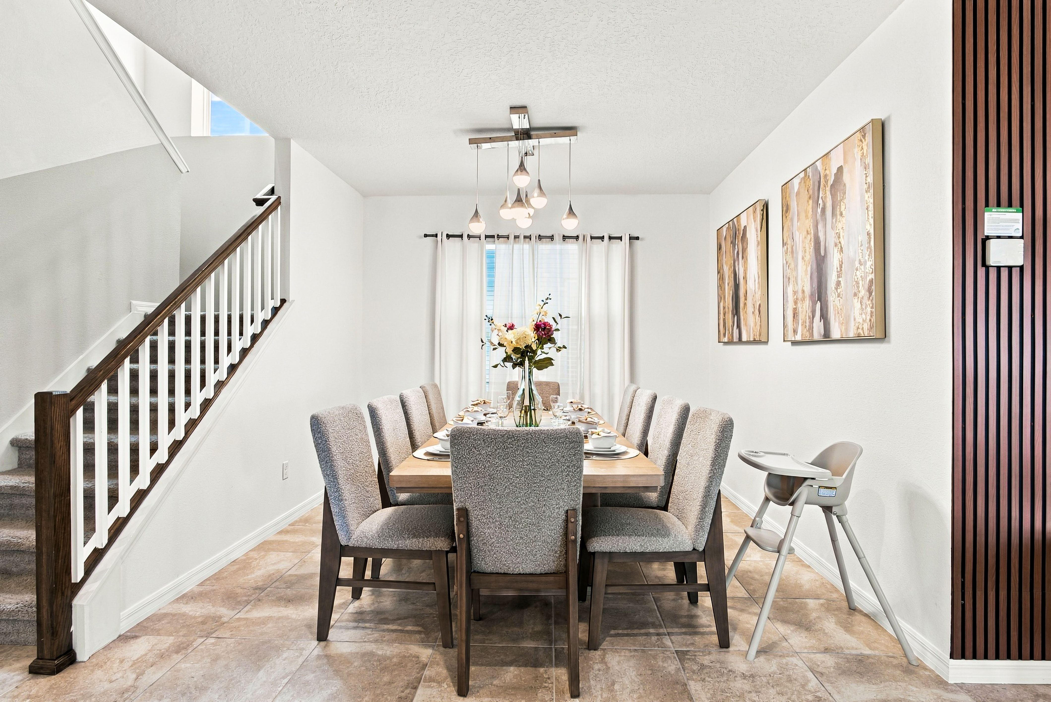 Bright dining area with seating for 8, modern lighting, and family-friendly touches