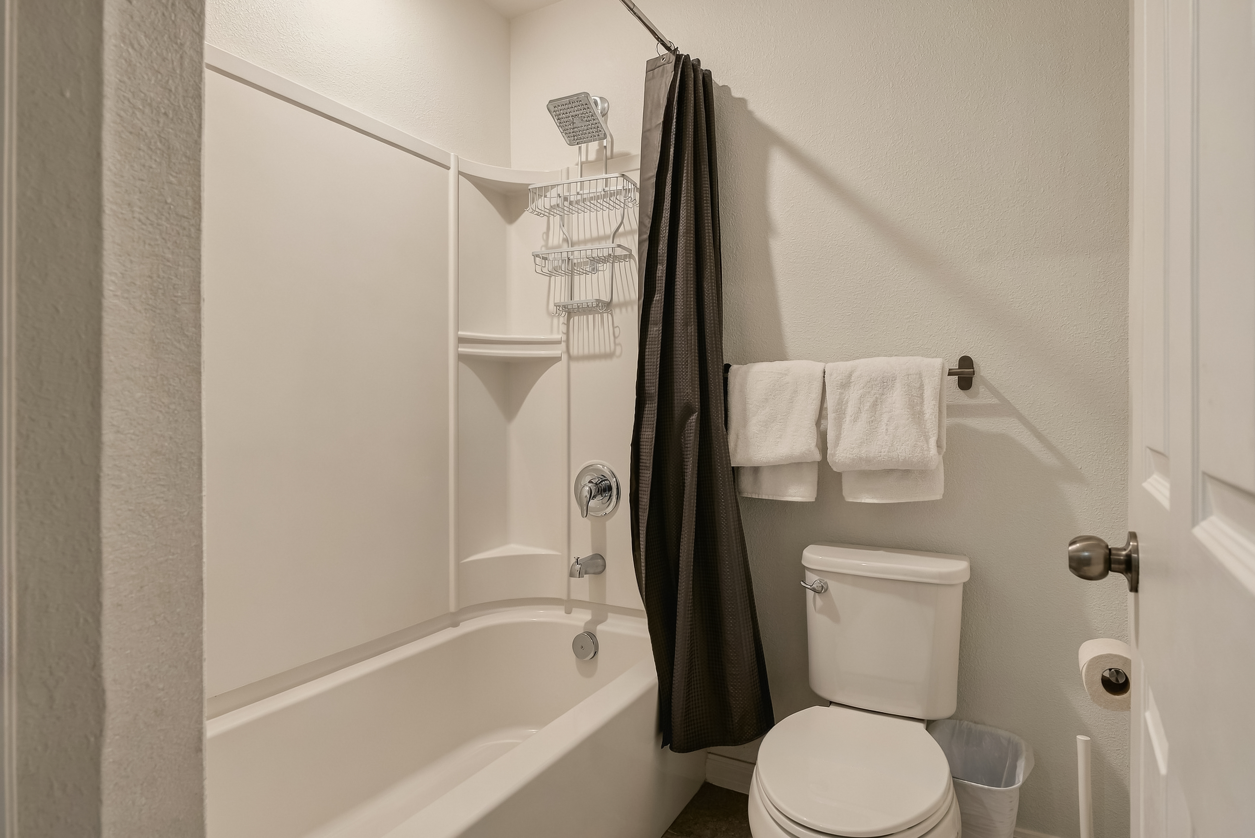 Clean full bathroom with tub-shower combo and handy guest storage