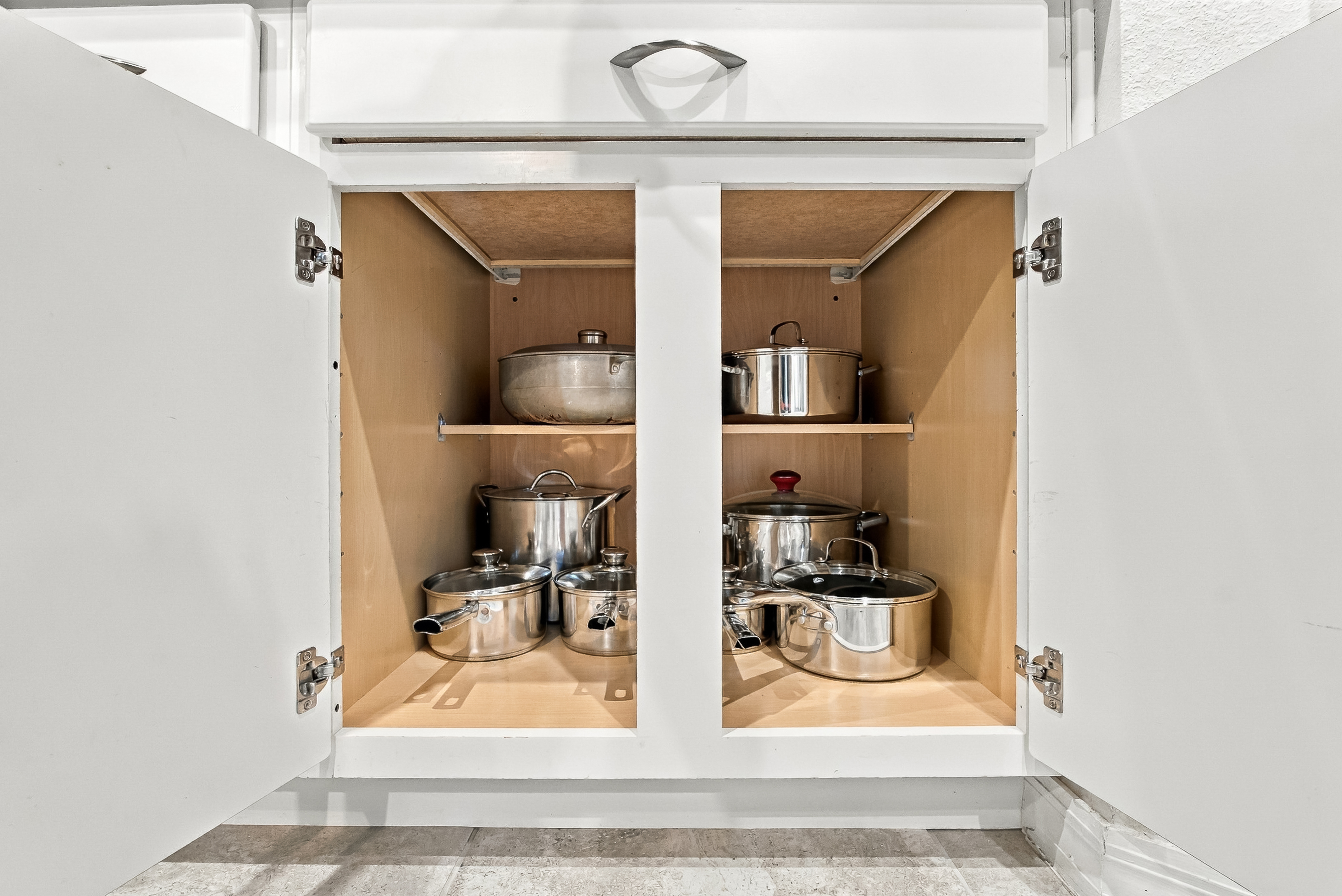 Well-stocked kitchen cabinet with organized pots and pans