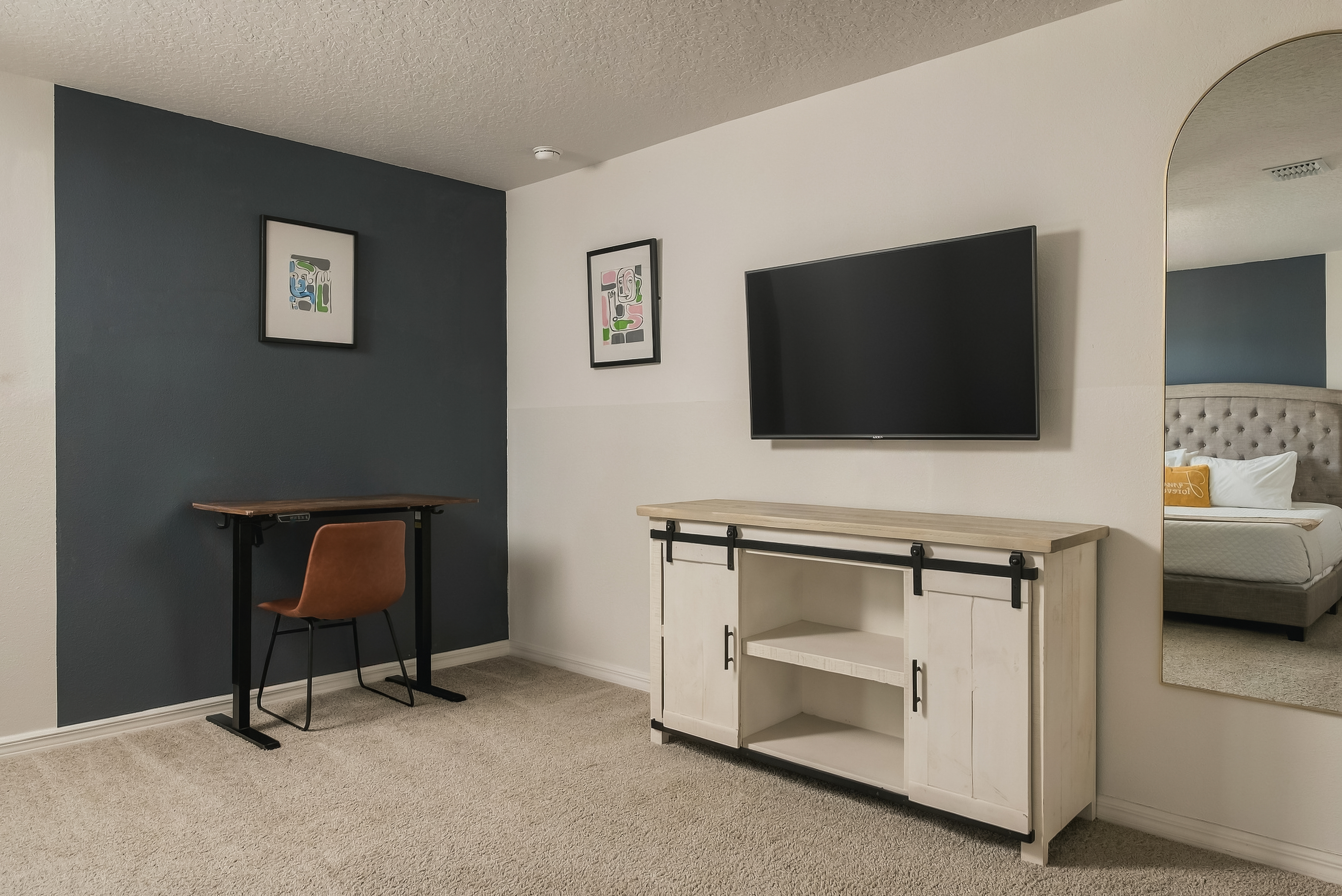 Modern bedroom with TV, workspace, and stylish accent wall