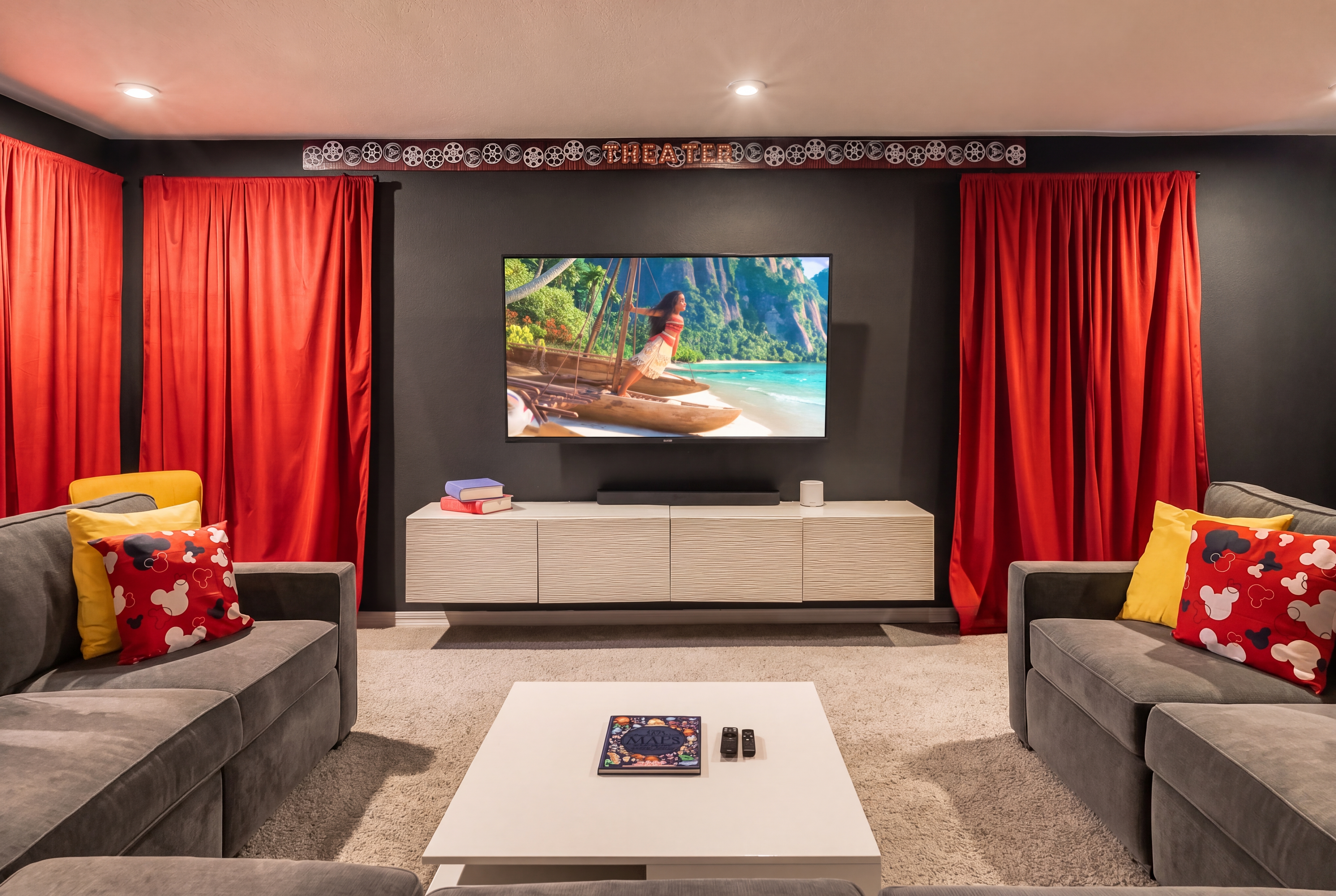 Private home theater with plush seating and a true cinematic vibe with a big-screen smart TV, Sound bar w/sub, oversized sectionals, and theater-style curtains — the whole family's favorite spot to pile in after a day at the parks.