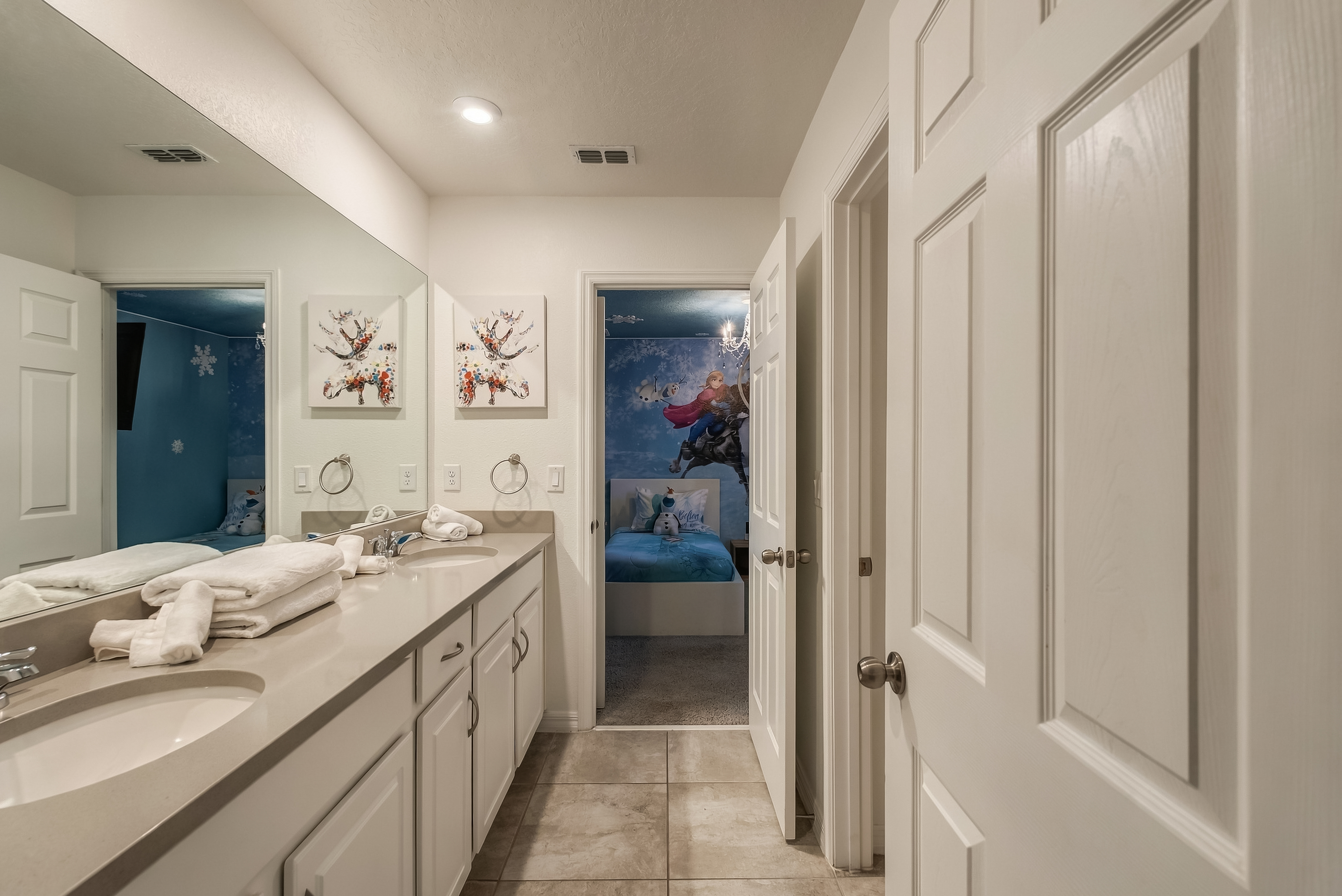 Spacious double-vanity bathroom with a clean look and themed bedroom access
