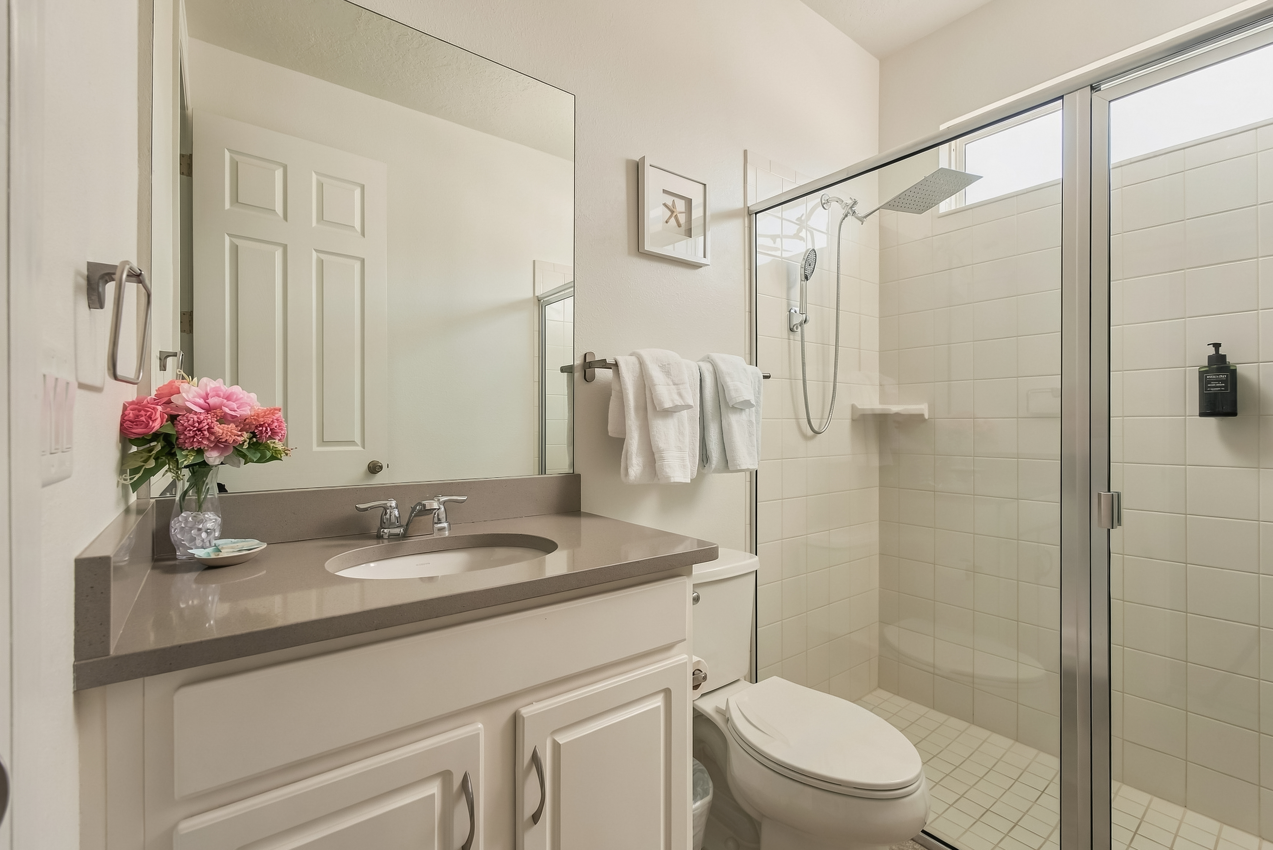 Bright modern bathroom with glass walk-in shower and spacious vanity