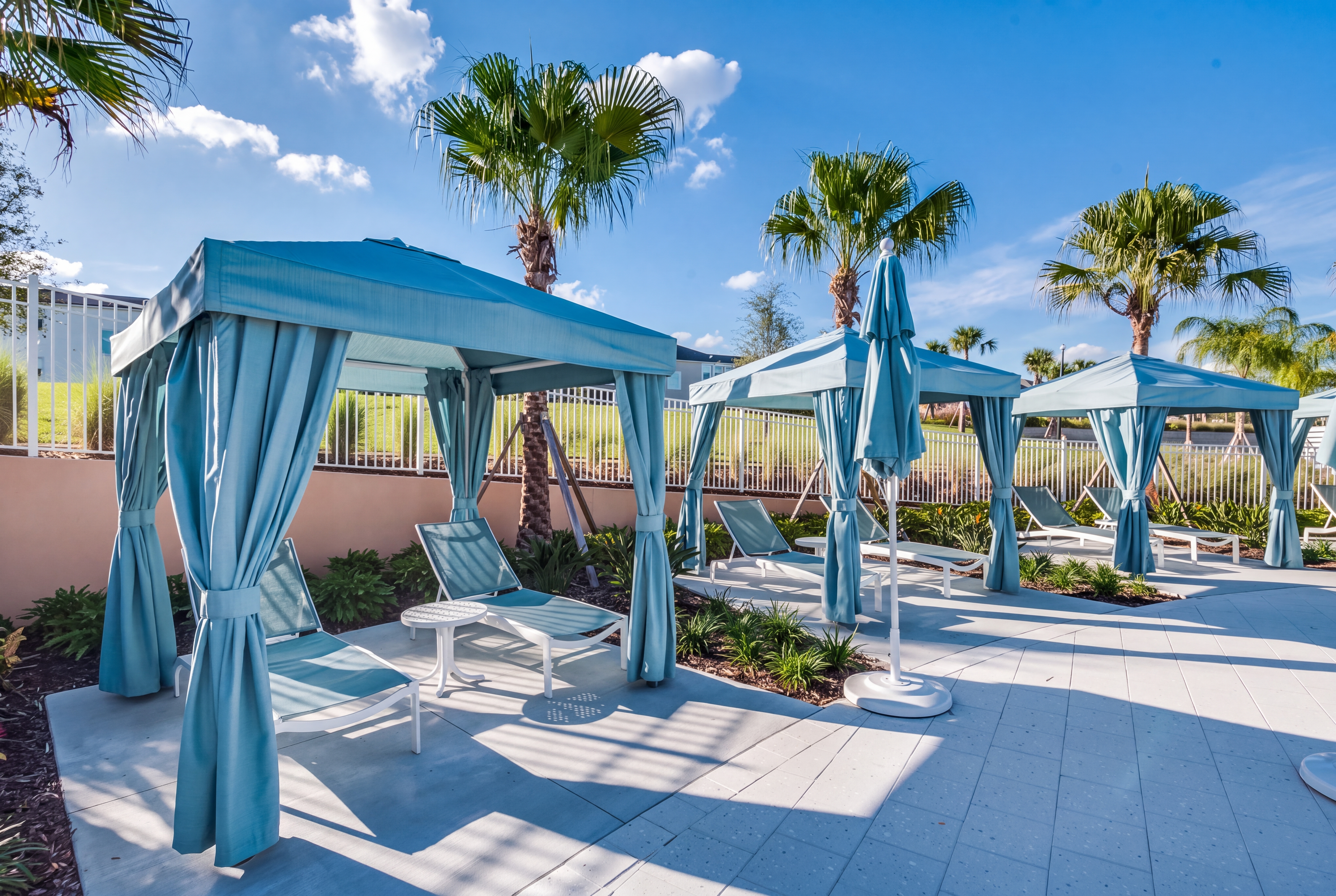 Resort-style pool cabanas with loungers and palm-lined tropical vibes